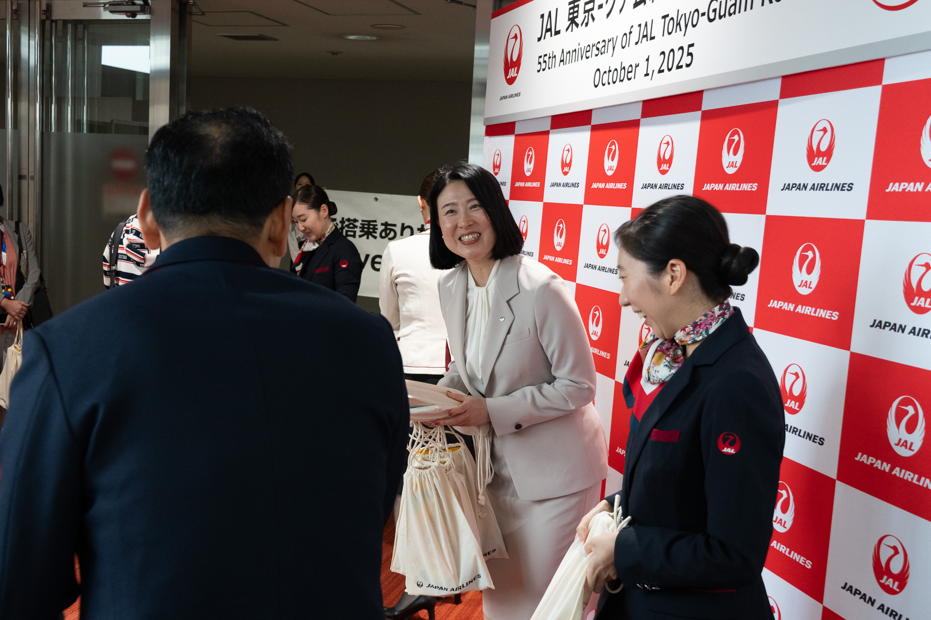 搭乗が始まるとチャモロダンサーも見送るなか、記念品の配布を行なった