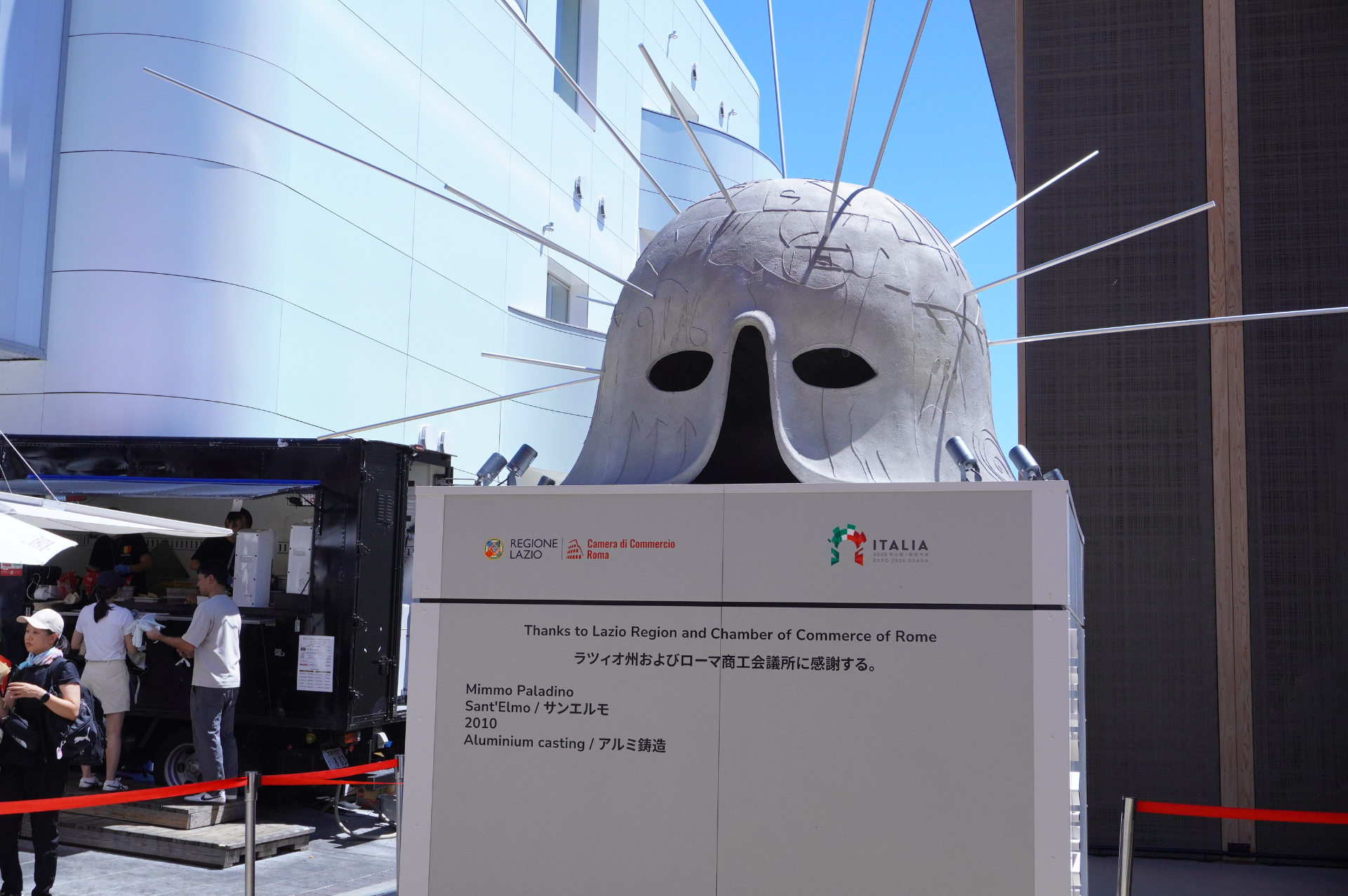 彫刻家ミンモ・パラディーノによる長いトゲを持つ兜の形をした巨大なアルミ彫刻など、建物のまわりにも作品を設置