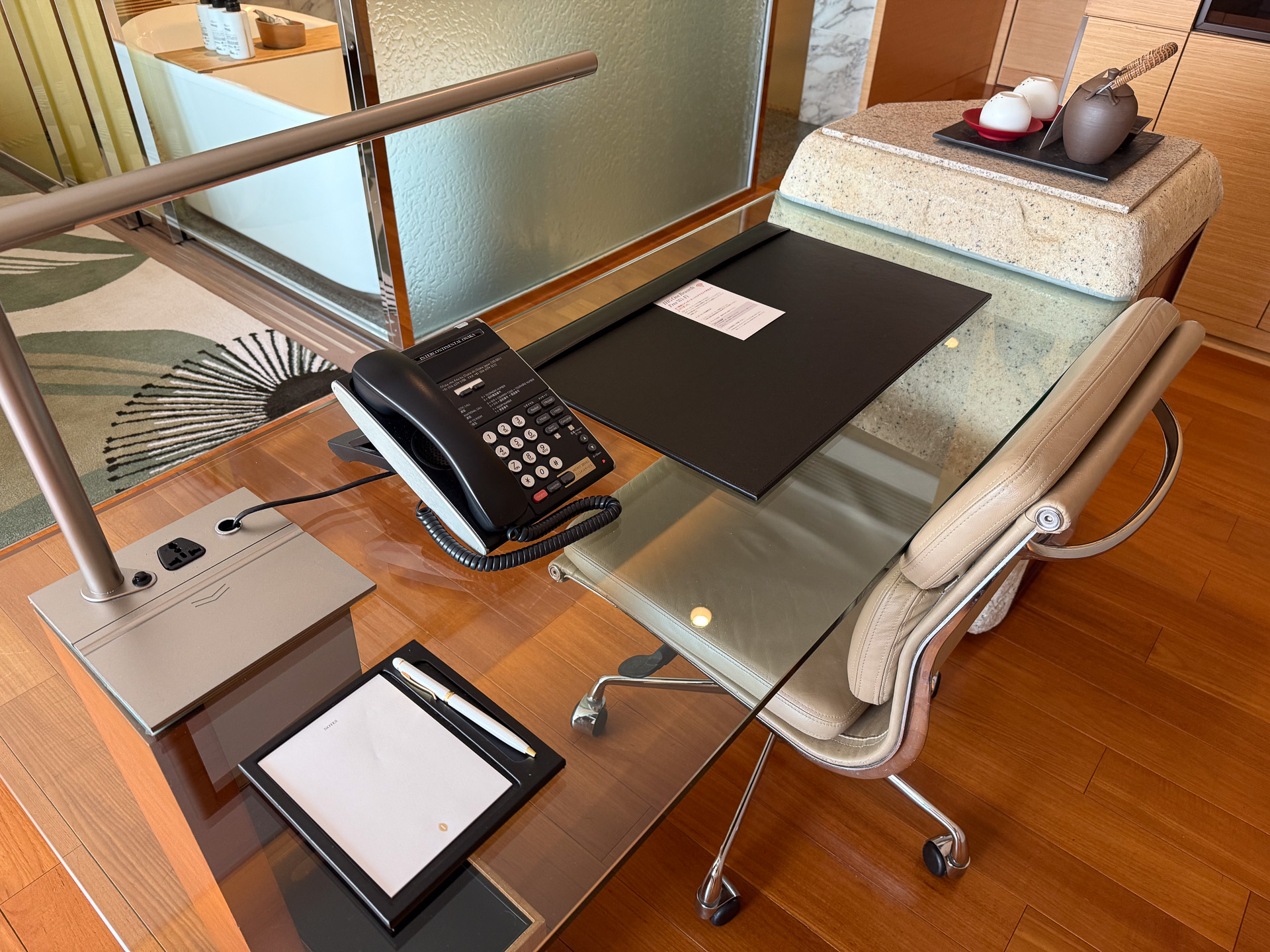 A glass desk and chair provide a proper workspace. A panel next to the power outlet opens to reveal a LAN port (cable in the drawer) and an HDMI port for connecting to the TV.