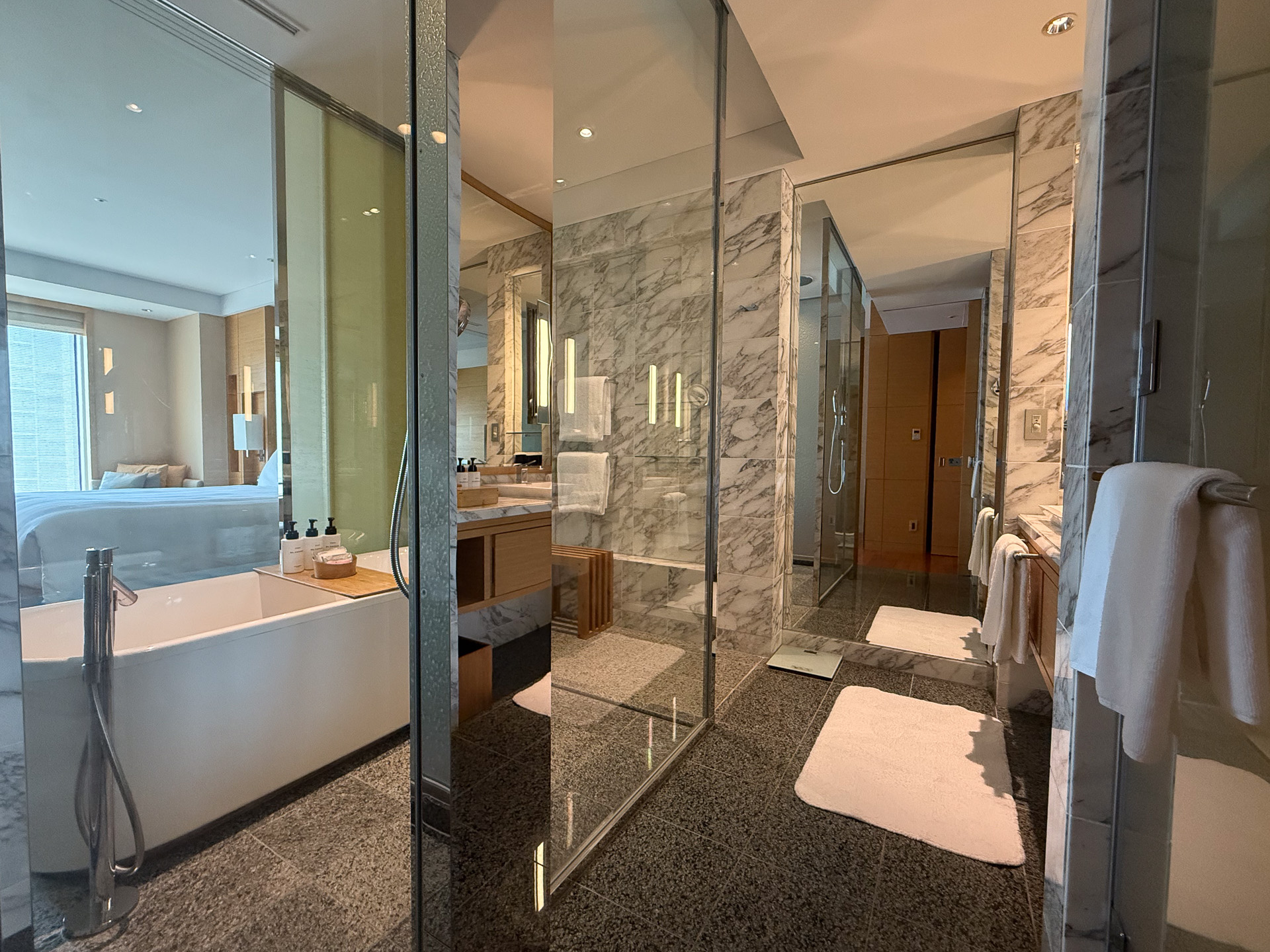 The washstand, toilet, and bathroom are all separate. The bathroom is glass-walled, visible from the bedroom, but can be concealed with a sliding door.