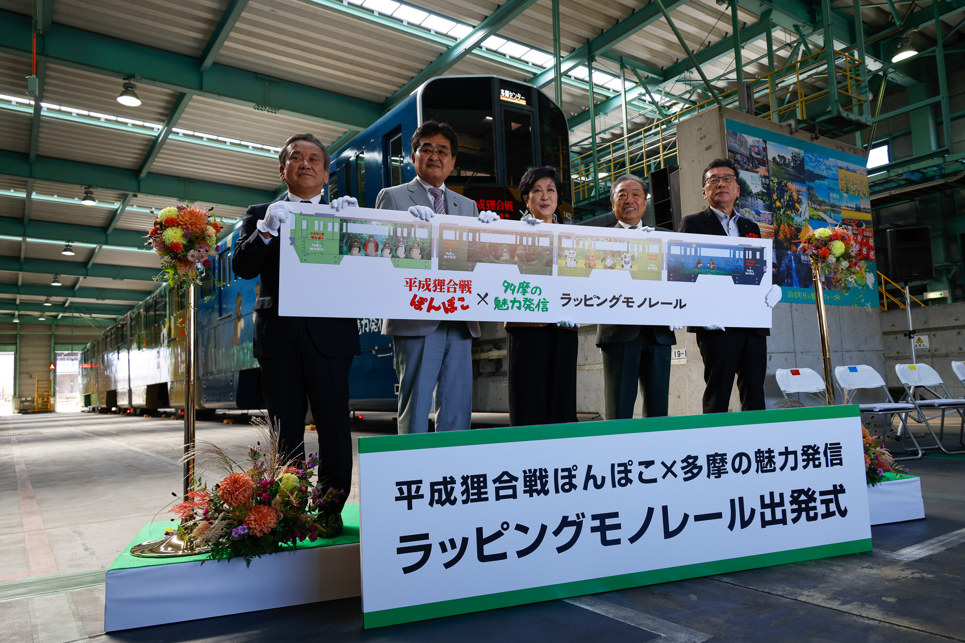 ラッピングモノレールのサイドビューを描いたボードを持ってのフォトセッション