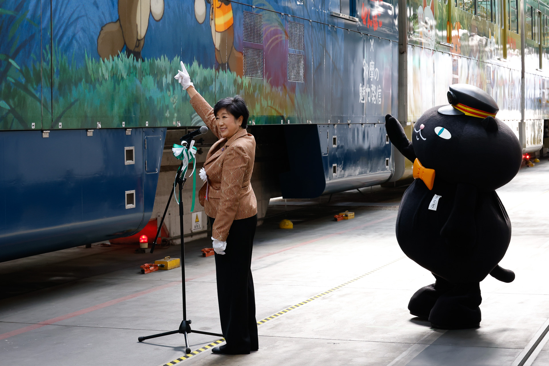 小池知事と、多摩都市モノレールのPR担当「タマオ」による出発式合図