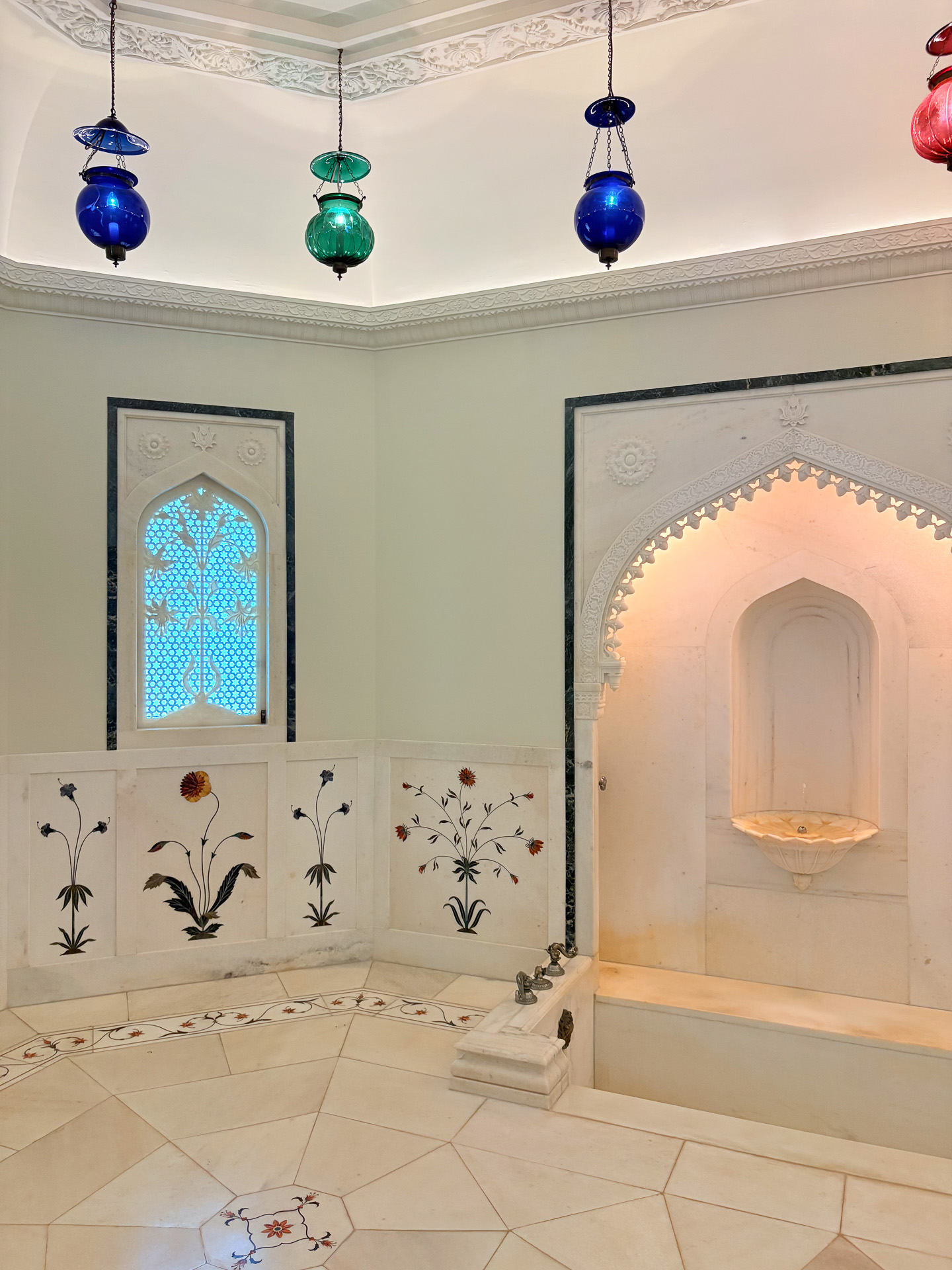 白い大理石に覆われたバスルーム。象嵌と呼ばれる工芸技法による花のデザインがぬくもりを感じさせる