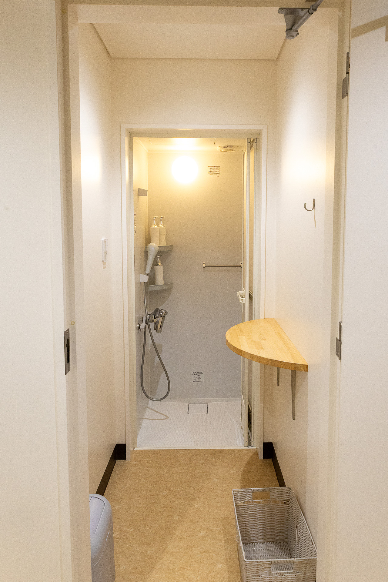 シャワーブース。手前の脱衣スペースの広さもあり、フックやテーブルがあるのも便利