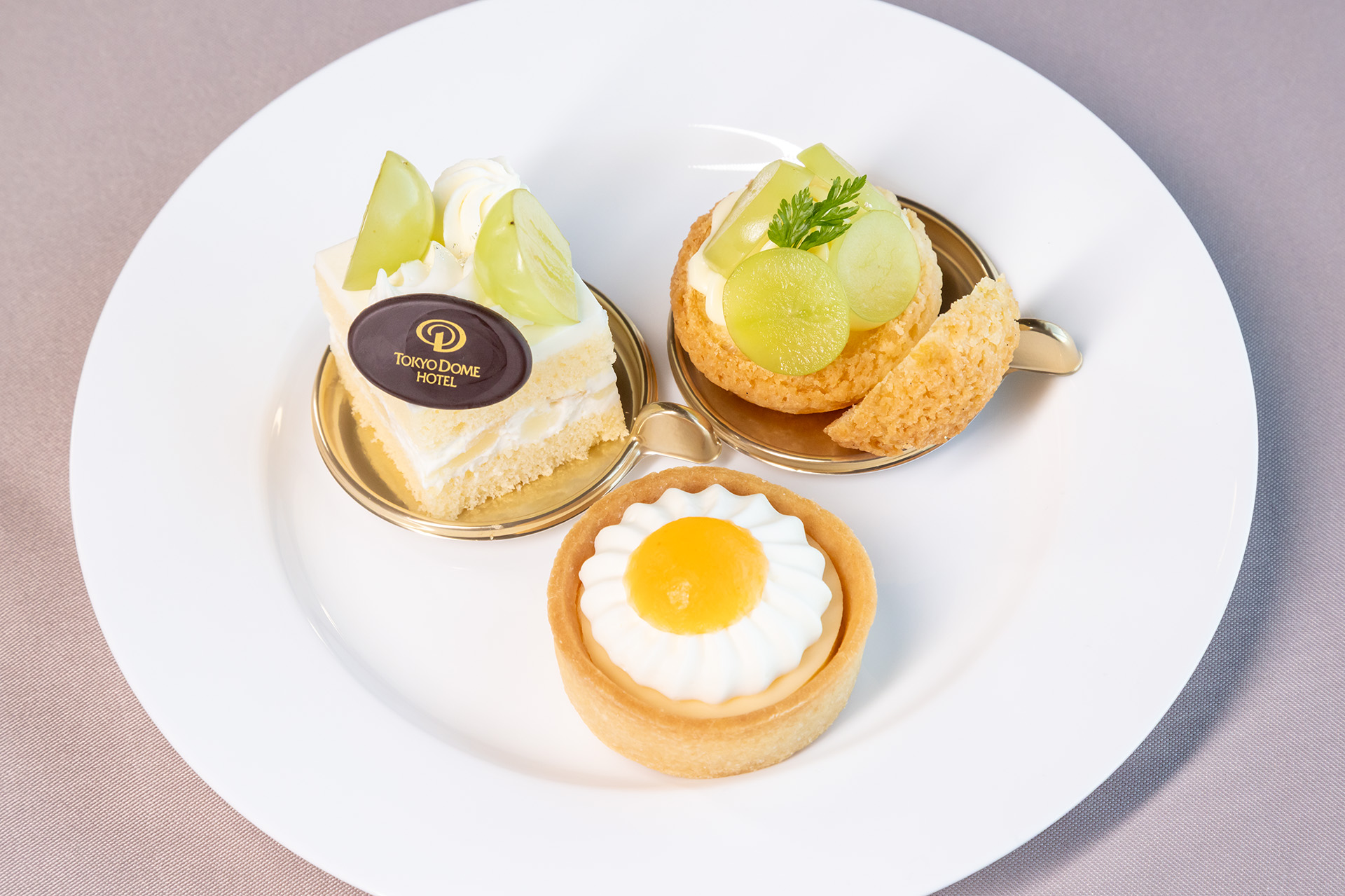 3種類のプチガトー。手前から右回りにレモンのタルト、シャインマスカットと洋梨のショートケーキ、シャインマスカットのシュークリーム