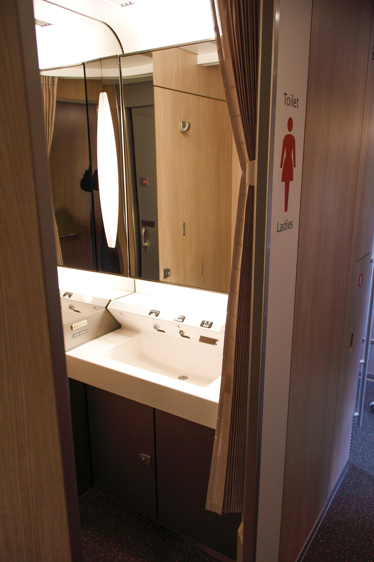 これはE5系の女性用洗面所。通常の洗面所と異なり、レール方向を向く配置で、背後から丸見えにならないよう配慮されている。その手前側に、トイレに出入りするための扉がある