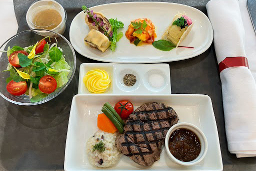 ホノルル行ビジネスクラス洋食。「静岡産国産牛ヒレのグリル三ヶ日みかんポン酢のソース浜松大平台高校の紫黒米リゾットを添えて」