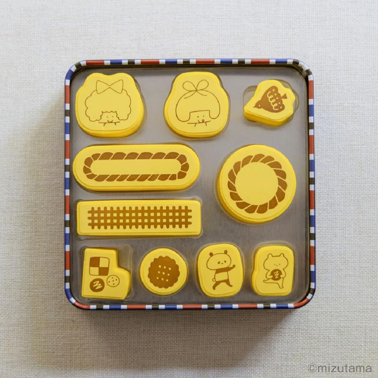 缶ケースサイズは約11×2.7×11cm（幅×奥行×高さ）。フタを開けるとクッキーみたいなはんこ10個が入っている