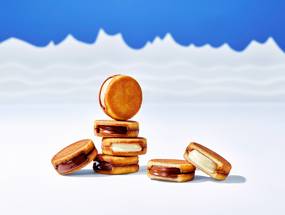 濃厚な放牧牛乳を使用した生チョコレートを、独自の“挟み焼き”で香ばしくカリカリ食感に仕上げたラングドシャで挟む「スノーサンド」（白/黒）