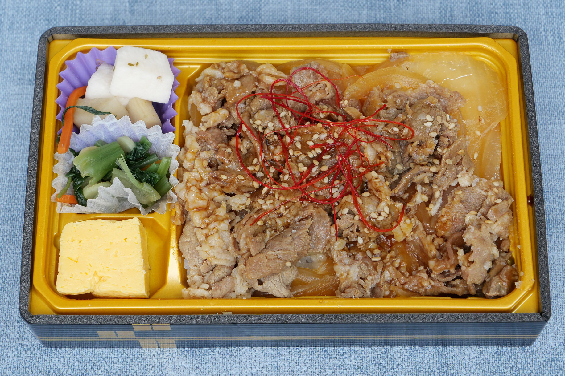 青森県産ごはんの上に、十和田バラ焼きのオリジナルの醤油ベースの甘辛いたれで炒めた玉ねぎと青森県産牛バラ肉が山盛り盛り付けられています