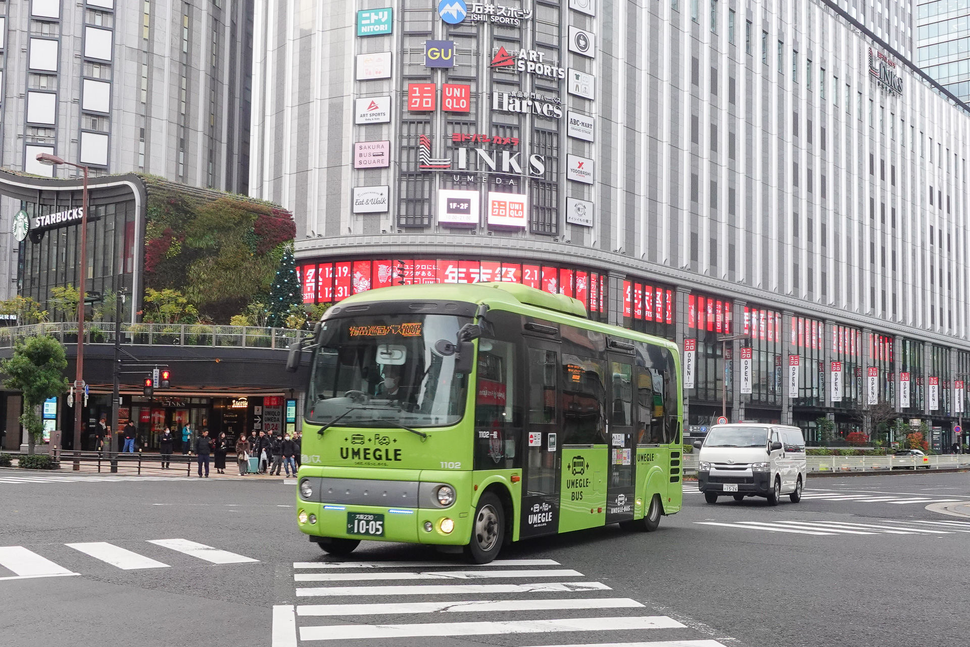 ヨドバシカメラ・マルチメディア梅田（LINKS UMEDA）をバックに走る「うめぐるバス」