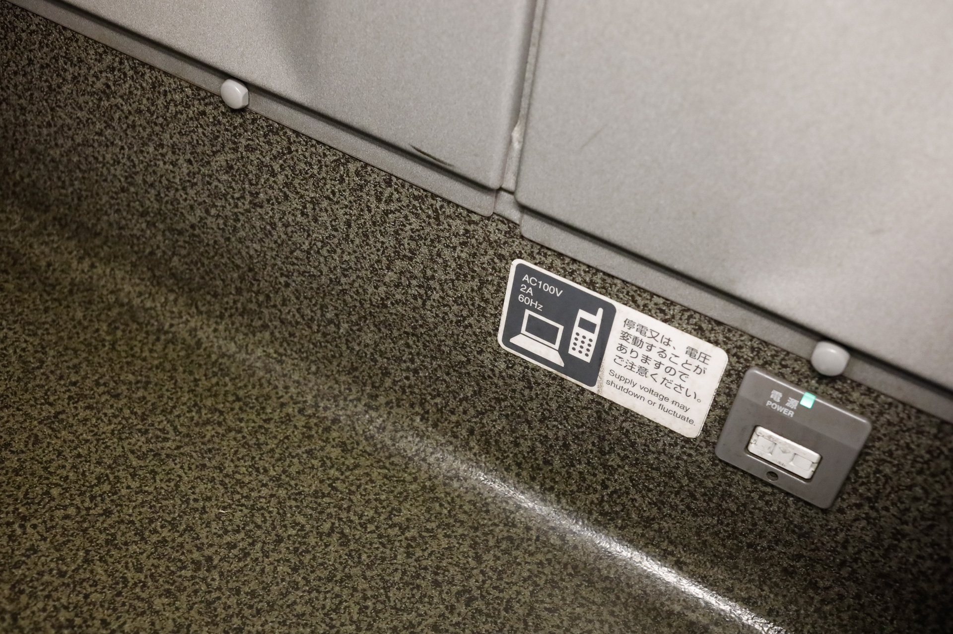N700系の普通車では、前後端の席を除いて、側壁の下方に電源コンセントがある。横の標記でお分かりのとおり、容量は2アンペアが上限だ
