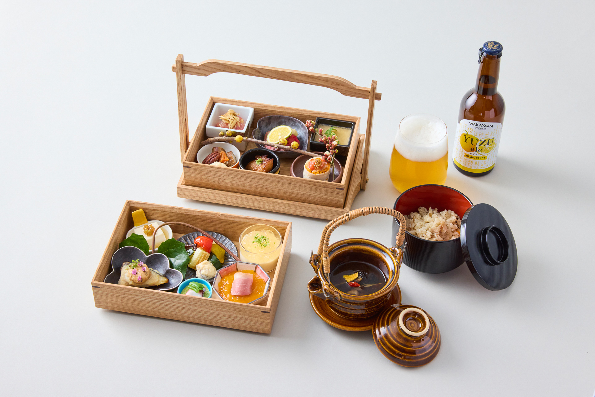 2026年春夏のランチメニュー。泉州蛸、じゃばら、有田みかん、河内鴨、湯浅もろみ、金山寺味噌、地元野菜を使用した12種類の小鉢をおかもちで。炊き込みご飯と土瓶蒸しをセットに