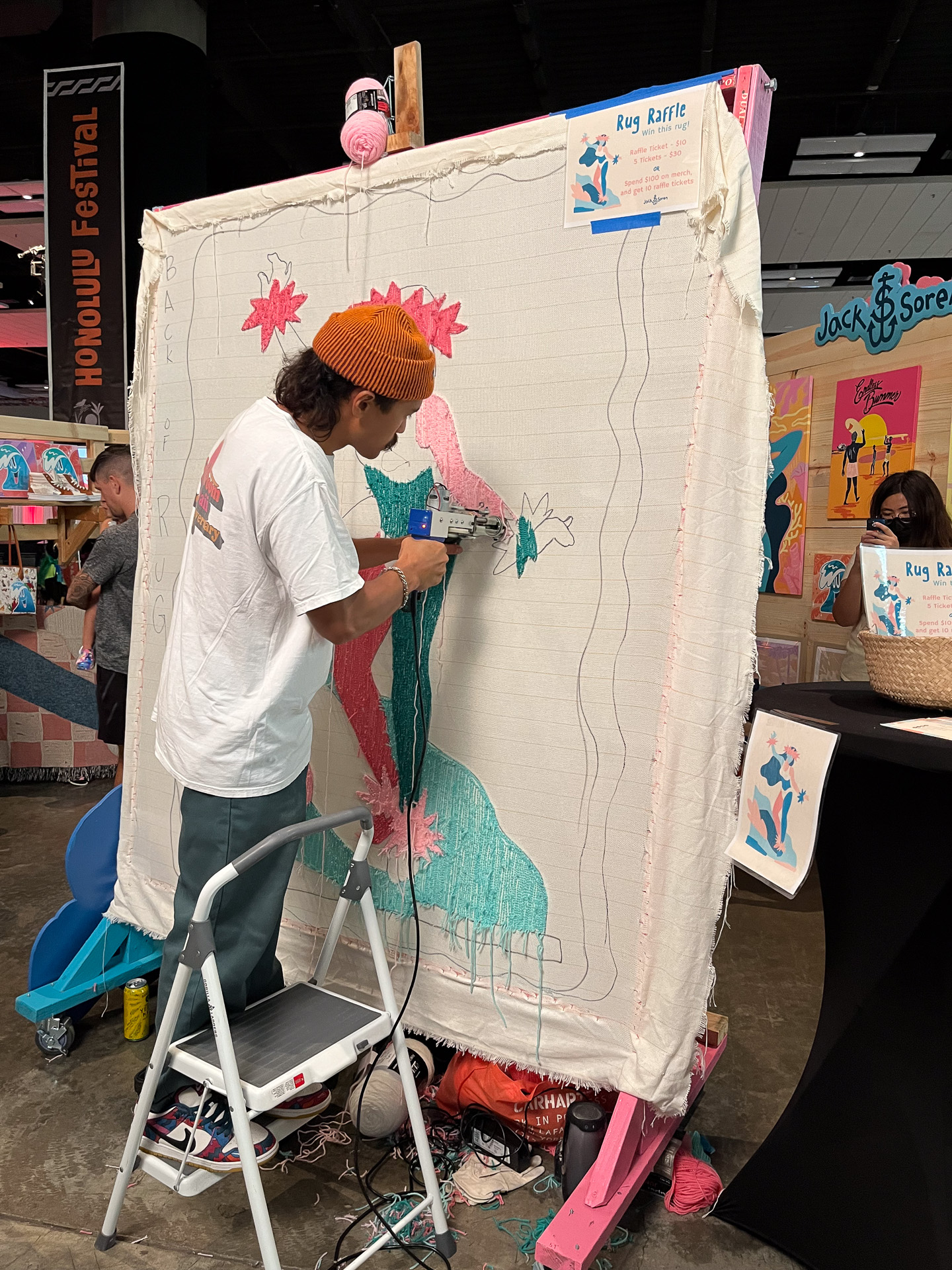 裏側からラグに刺繍を施すアーティスト。表側に回ると、右の写真のようになっていた