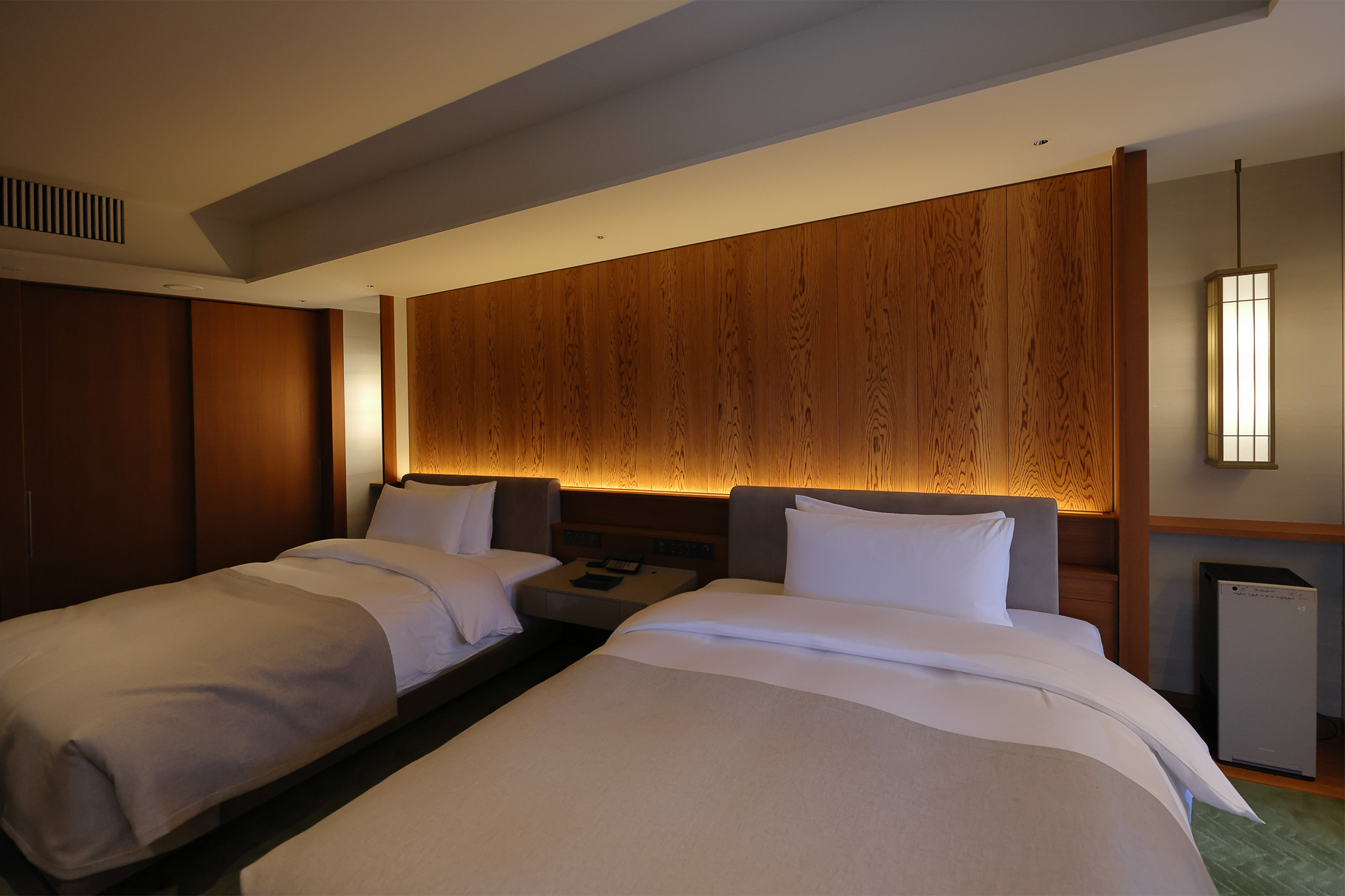 「弥栄スイート」のベッドルーム。ヘッドボードと一体になっている大きな杉板の模様が美しい。客室のヘッドボードには吉野杉など全国5か所の産地のものを使用しているという