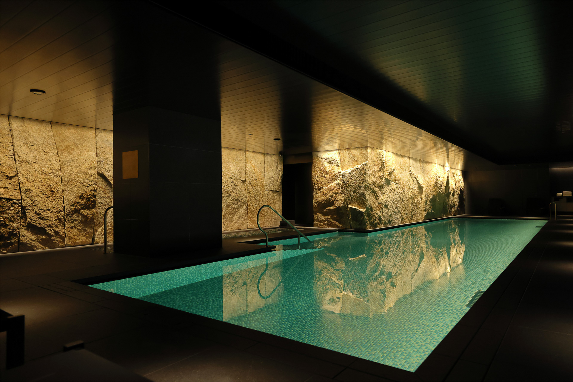 壁面には弥栄会館時代に外壁の一部に使用された北木石を使用。まるで洞窟と地下水脈のよう