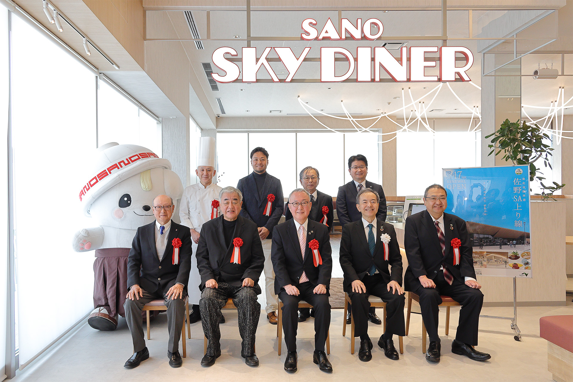 主催者や内覧会での登壇者、来賓で記念写真。佐野のブランドキャラクター「さのまる」も参加した