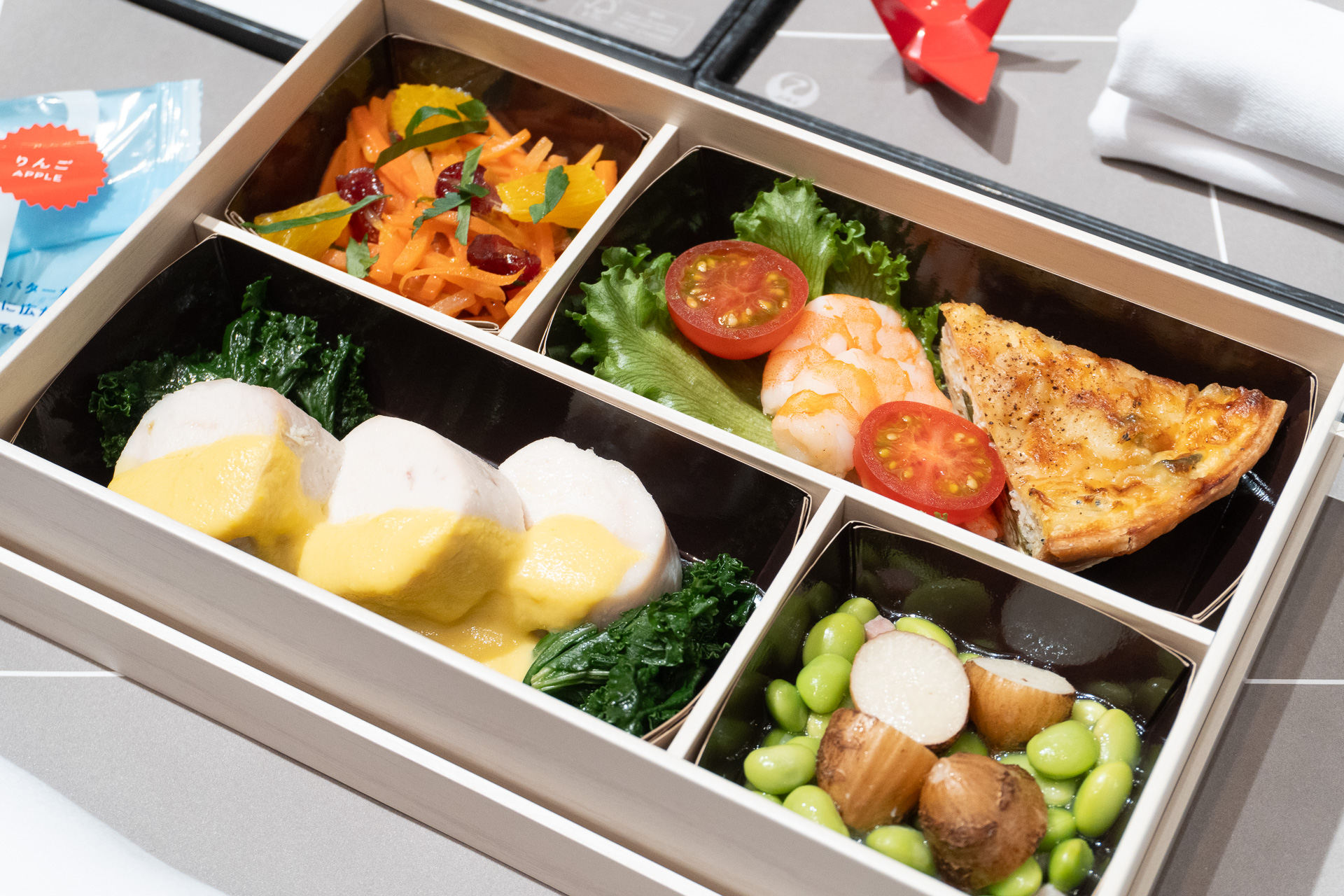短いフライトでもゆとりを持って味わえる“お弁当”の機内食。4～5月のメニューは青森県産チキンロール、ワカメとシラスのキッシュ、キャロットラペ、MILK STAR サンド りんごなど
