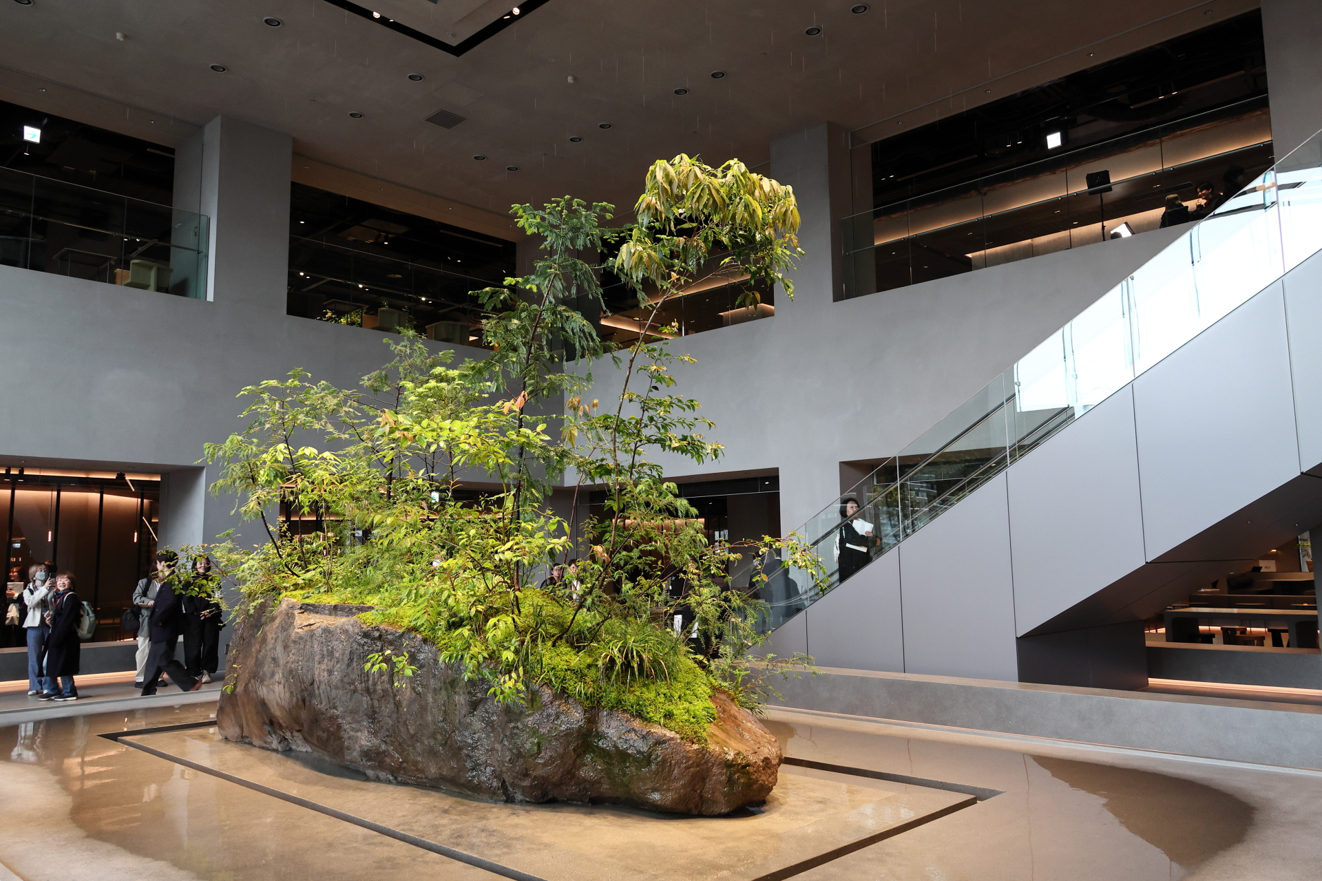 真鶴半島で採掘した岩の上に日本の山々の植物が育つ翠岩が印象深い「ニュウマン高輪 ミムレ」2階。吹き抜け空間に人工の雨が降ってくる