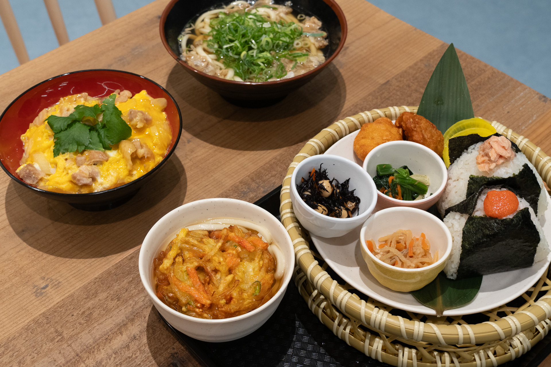 写真手前はおにぎりやミニかき揚げうどん、唐揚げ、惣菜などをセットにした「選べるおにぎり御膳」（1500円）
