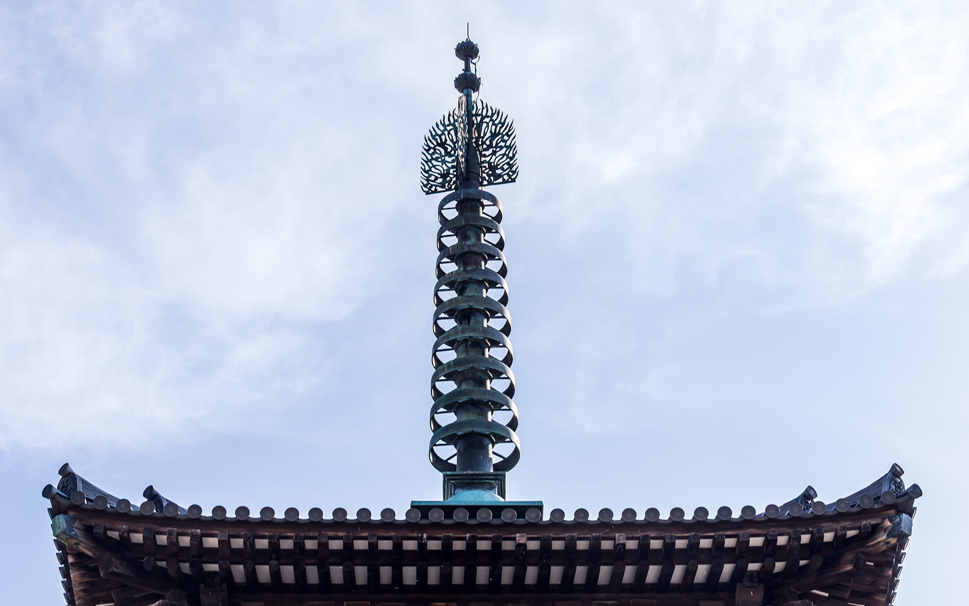 東塔の相輪上部にある水煙にはさまざまな天人がデザインされている。この写真で分かりやすいのは下部中央寄りの「笛を吹きながら踊る奏楽天人」