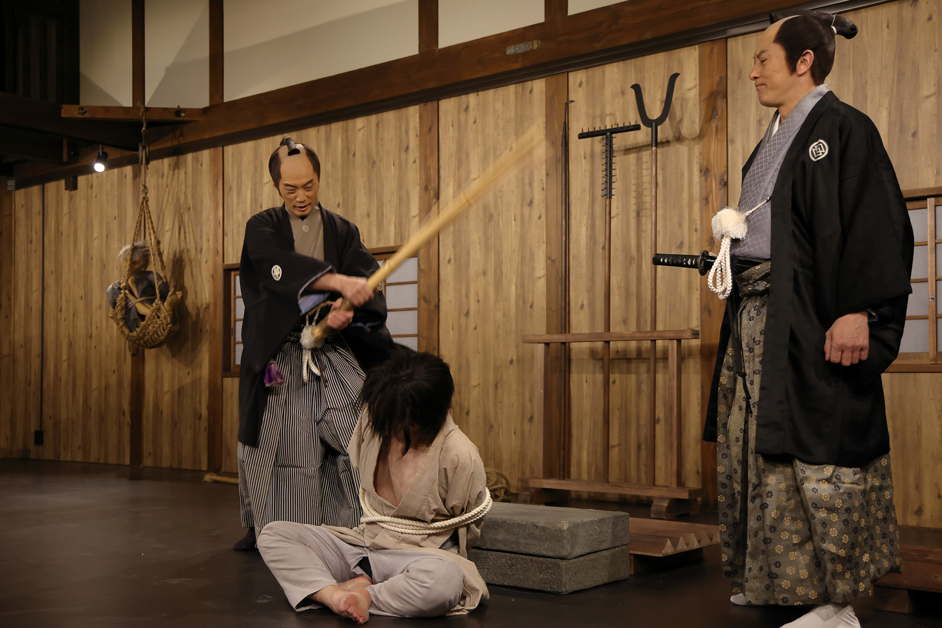 壱之間 夜の演目「大人しか入れない拷問屋敷」。竹を割った箒尻（ほうきじり）と呼ばれる道具で責問をする様子