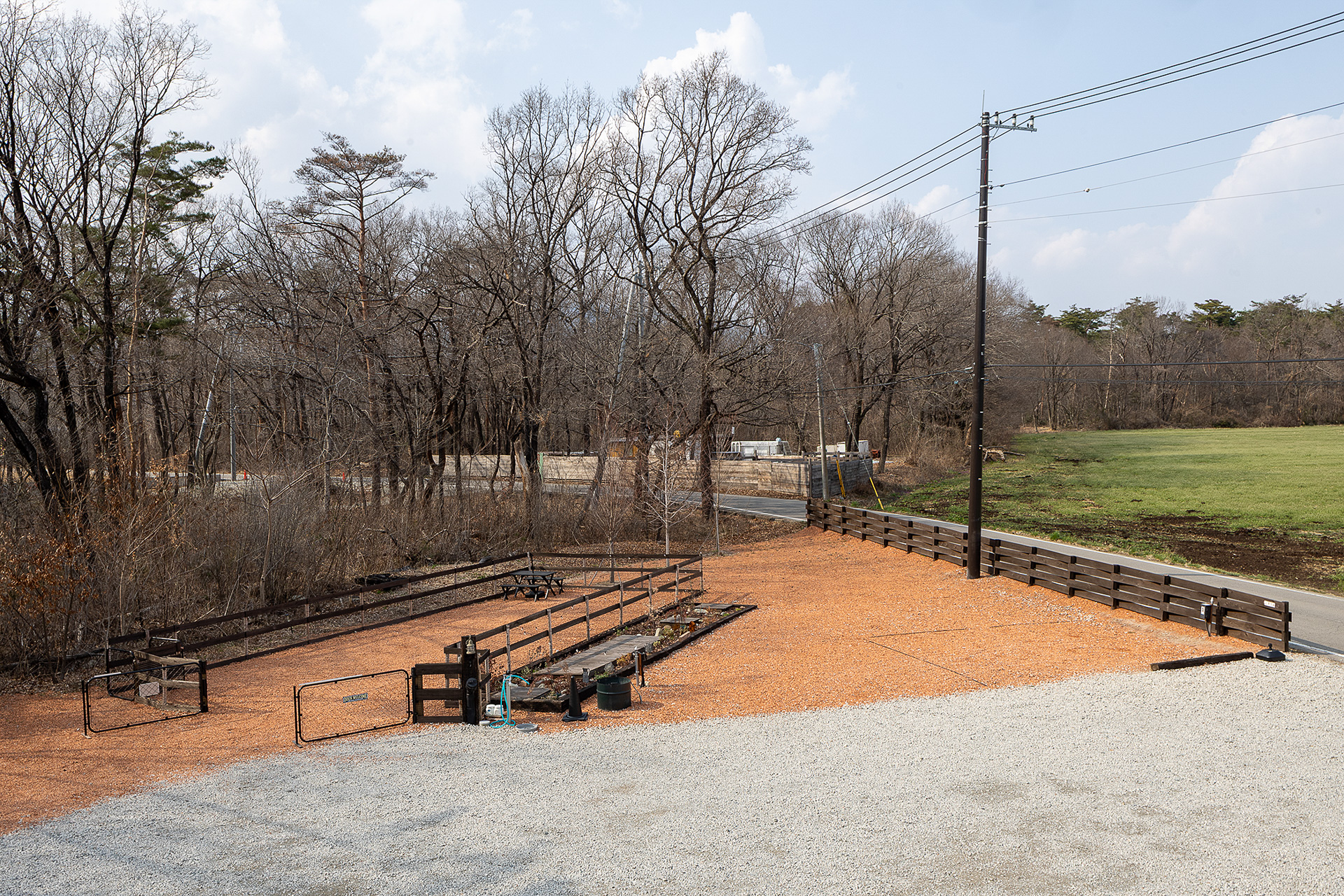 前面道路沿いに「道路側サイト」がある（8×6m）。写真左側のフェンスに囲まれているところが「林側サイト」。こちらはドッグフリーサイトで、奥行き15mで幅は6～7mの変形サイズ