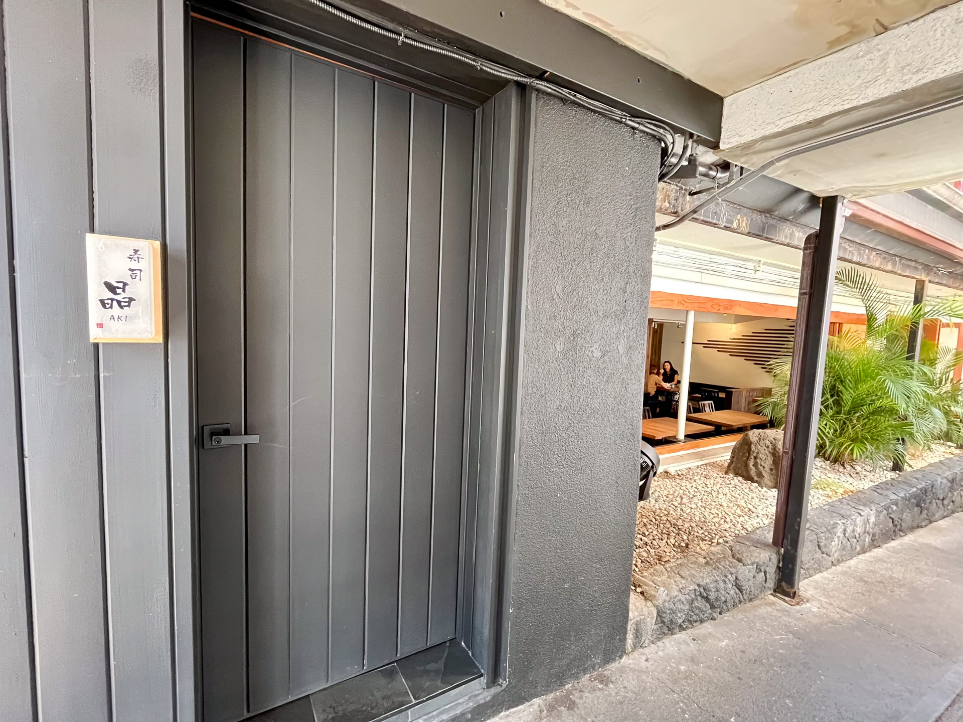 黒塗りの隠れ家的な門構え（手前）。右奥は多くの常連客でにぎわう「ジャパニーズレストラン彩季」