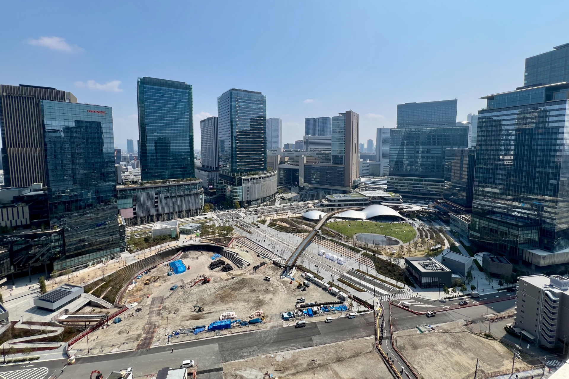 写真左手が「うめきた公園 ノースパーク」（2025年3月時点の整備中のようす）、右手が「うめきた公園 サウスパーク」（2024年9月に開園）。中央斜めの橋は、南北をつなぐ「ひらめきの道」