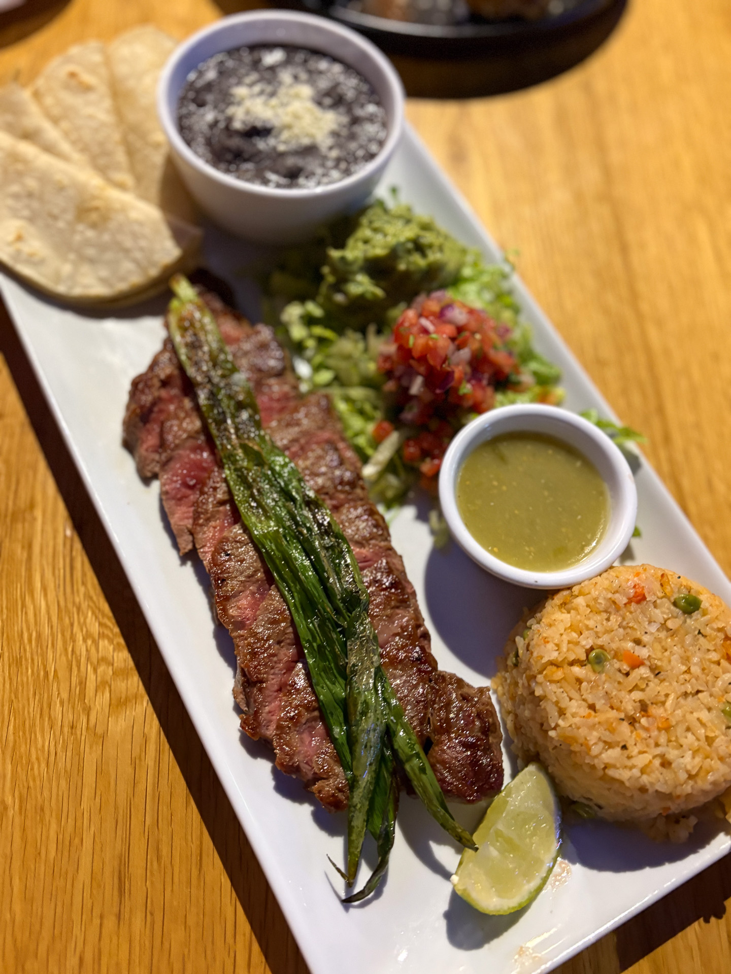 ミディアムに焼かれたステーキ肉、サルサ、ワカモレを挟んでタコスにするカルネアサダプレート