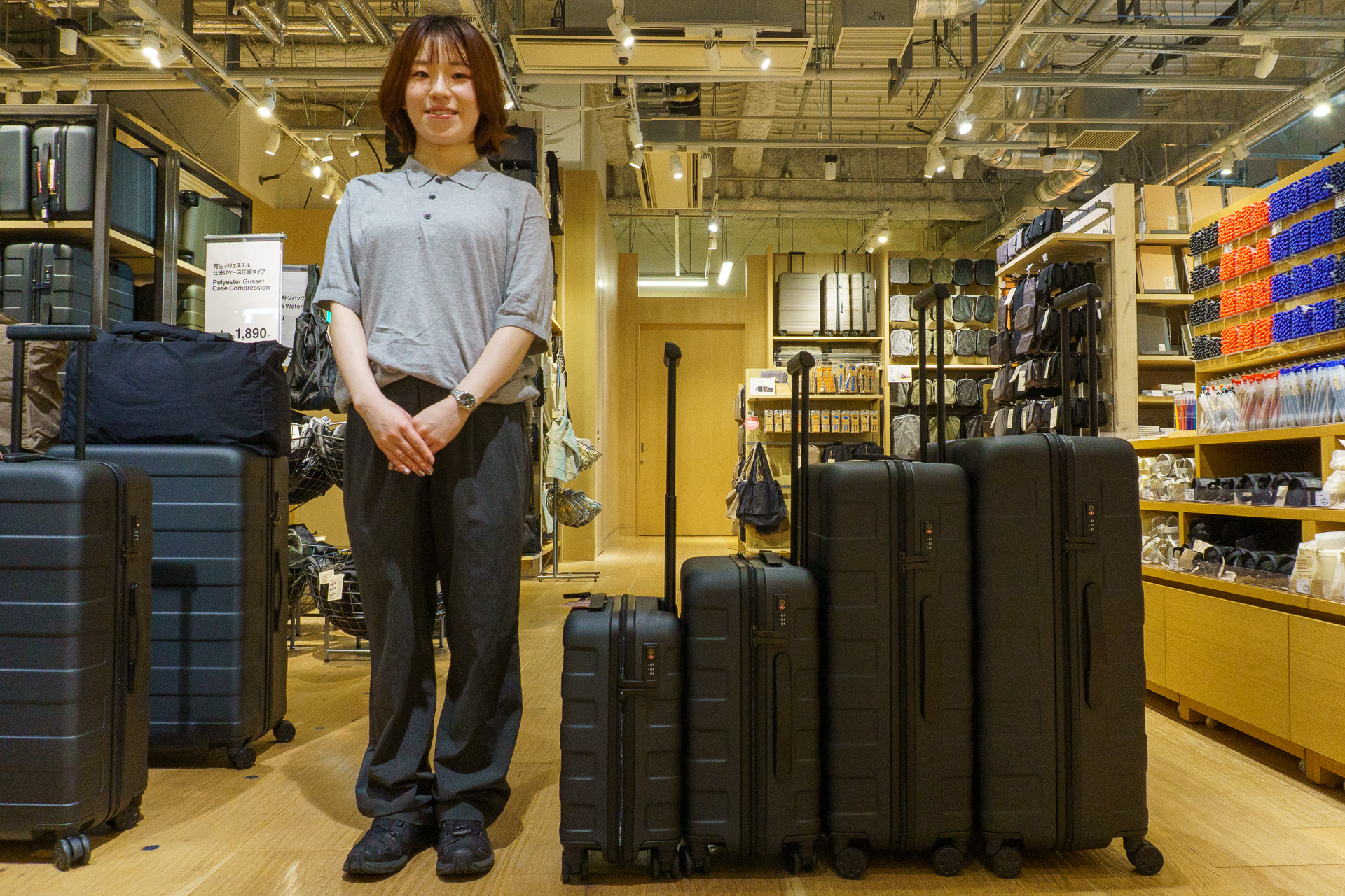 「無印良品 銀座」4階フロアマネージャー 森菜々子氏（左）。4サイズの新キャリーケースを並べた様子