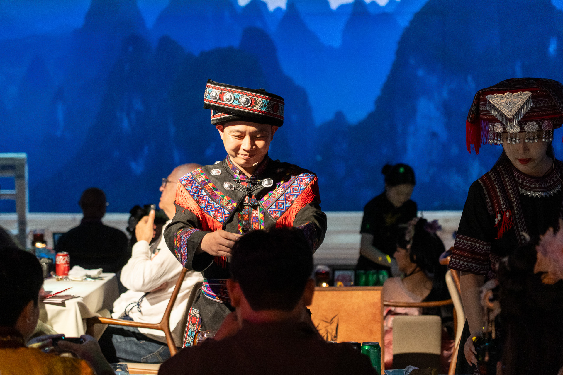 桂林の美しい山々を背景に、伝統衣装をまとったスタッフが料理をサーブしてくれます