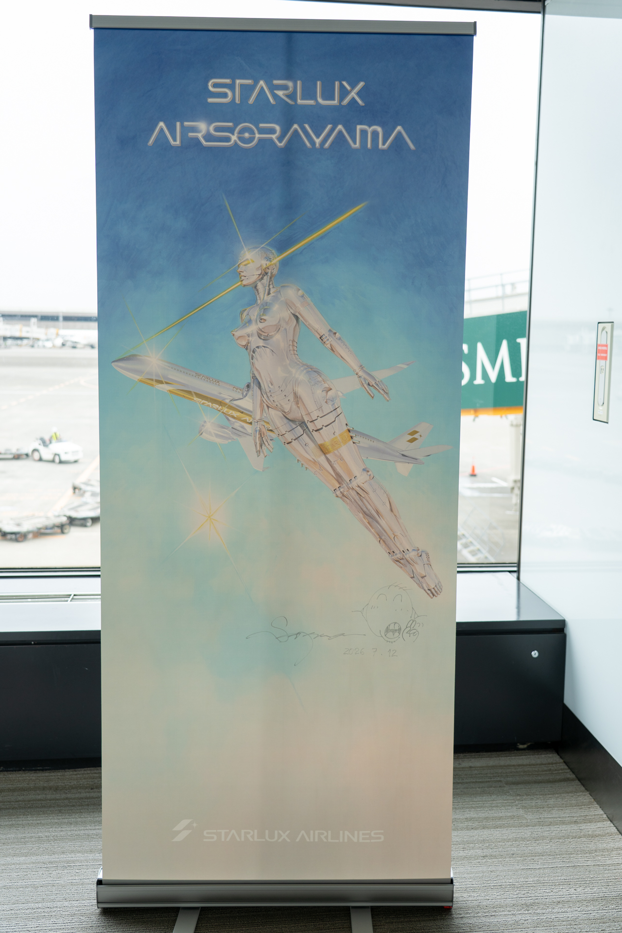62番ゲート前に設置された「STARLUX AIRSORAYAMA」の記念バナー。右下には空山基氏によって書き入れられた直筆のサインが