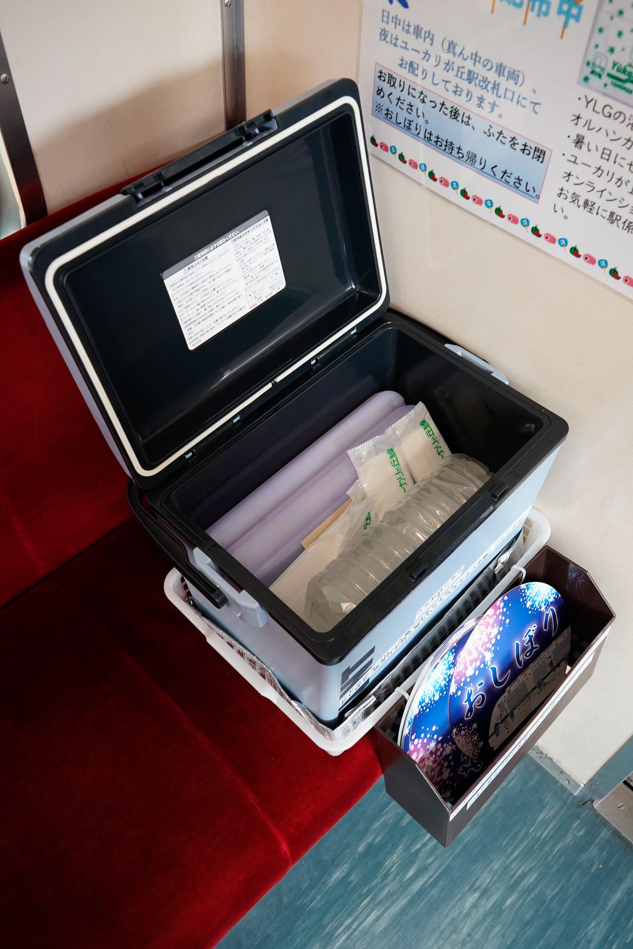 3両編成の2両目にクーラーボックスを設置して、そこに保冷剤とおしぼりを入れている。その横には団扇を入れた箱も