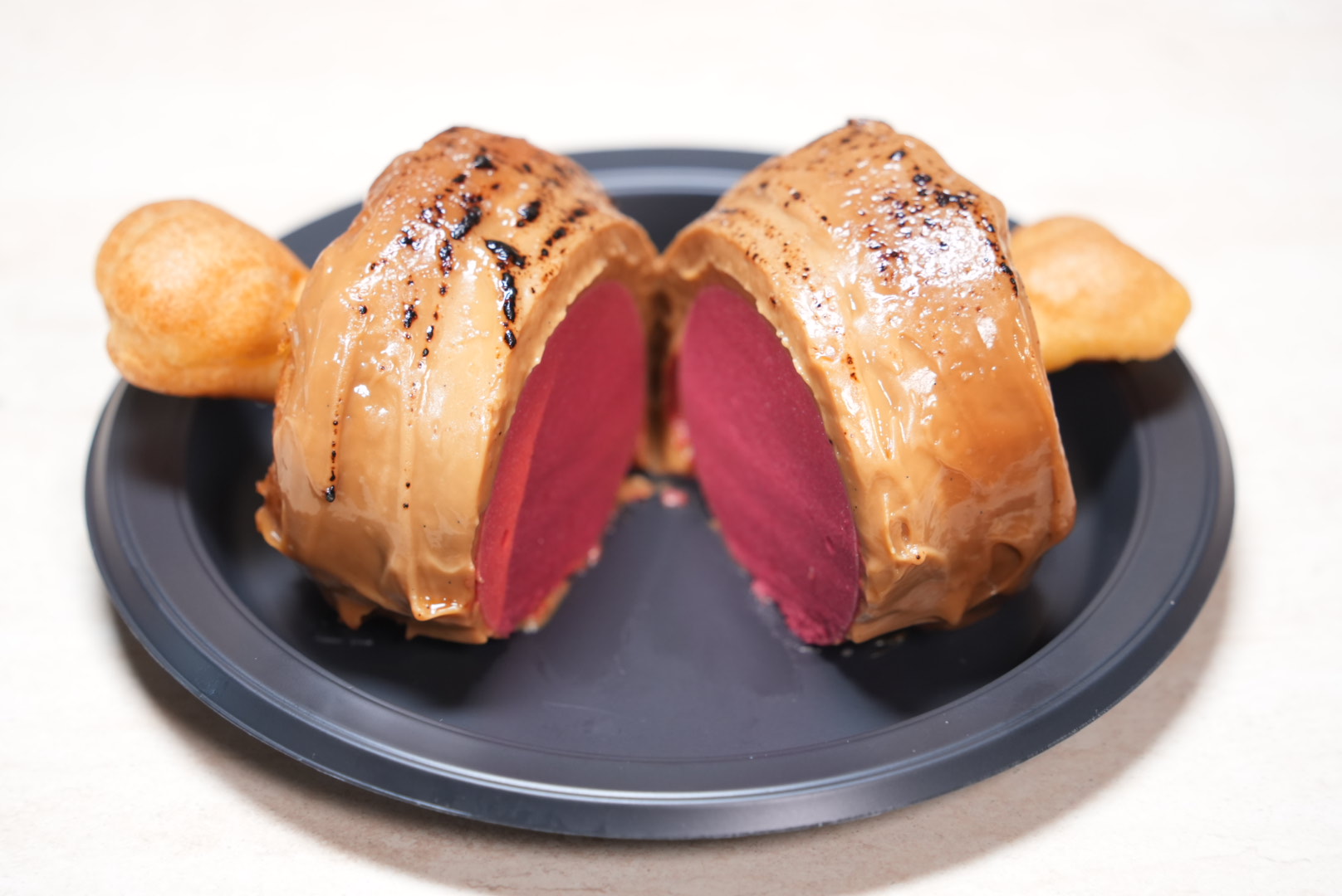 A cross-section of "Luffy's Meaaat! Raspberry & Salted Caramel Mousse." The raspberry mousse cleverly mimics the look of "medium-rare meat."