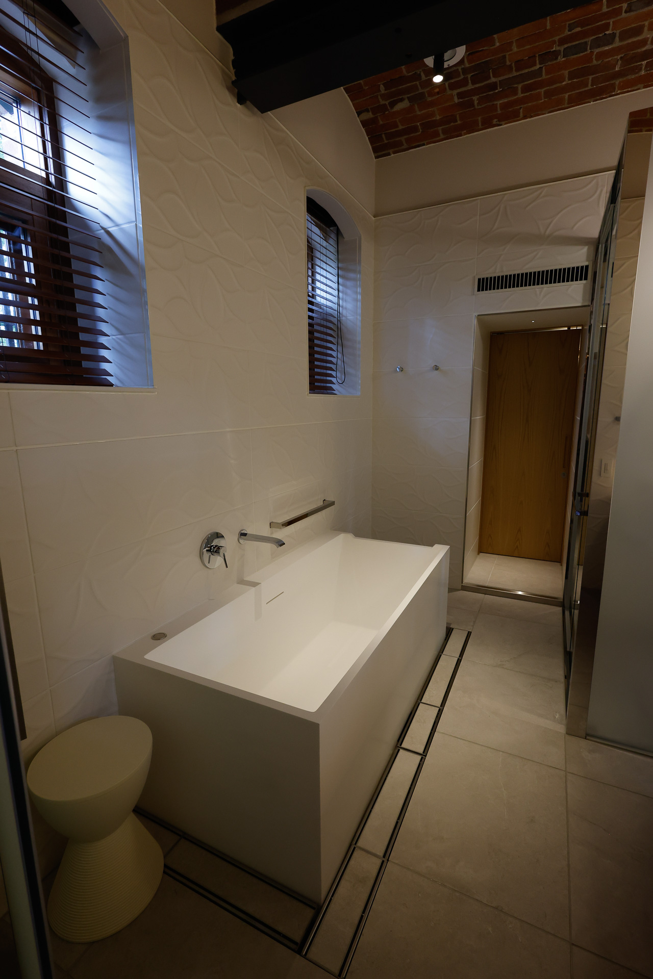 複数の舎房をつないで客室に改装している。バスタブとシャワーブース、その奥にはトイレがあり、おそらくは配管設備の関係で、ここだけ床が高くなっている