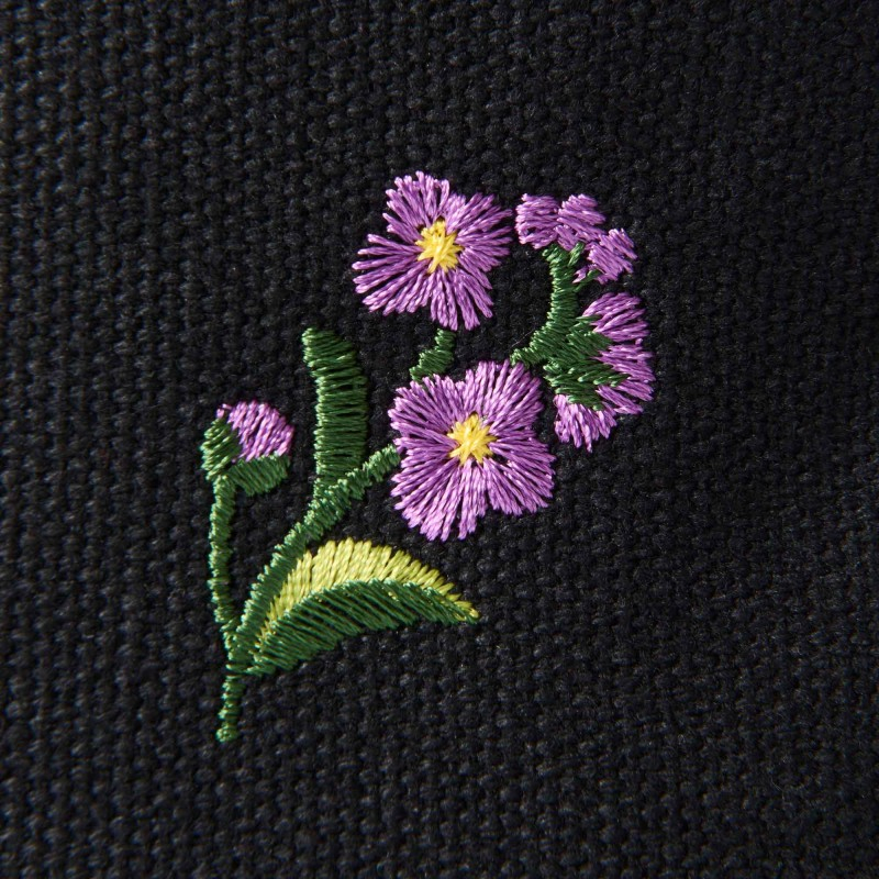 黒のキャンバス生地にカラフルな花柄の刺繍をあしらっている