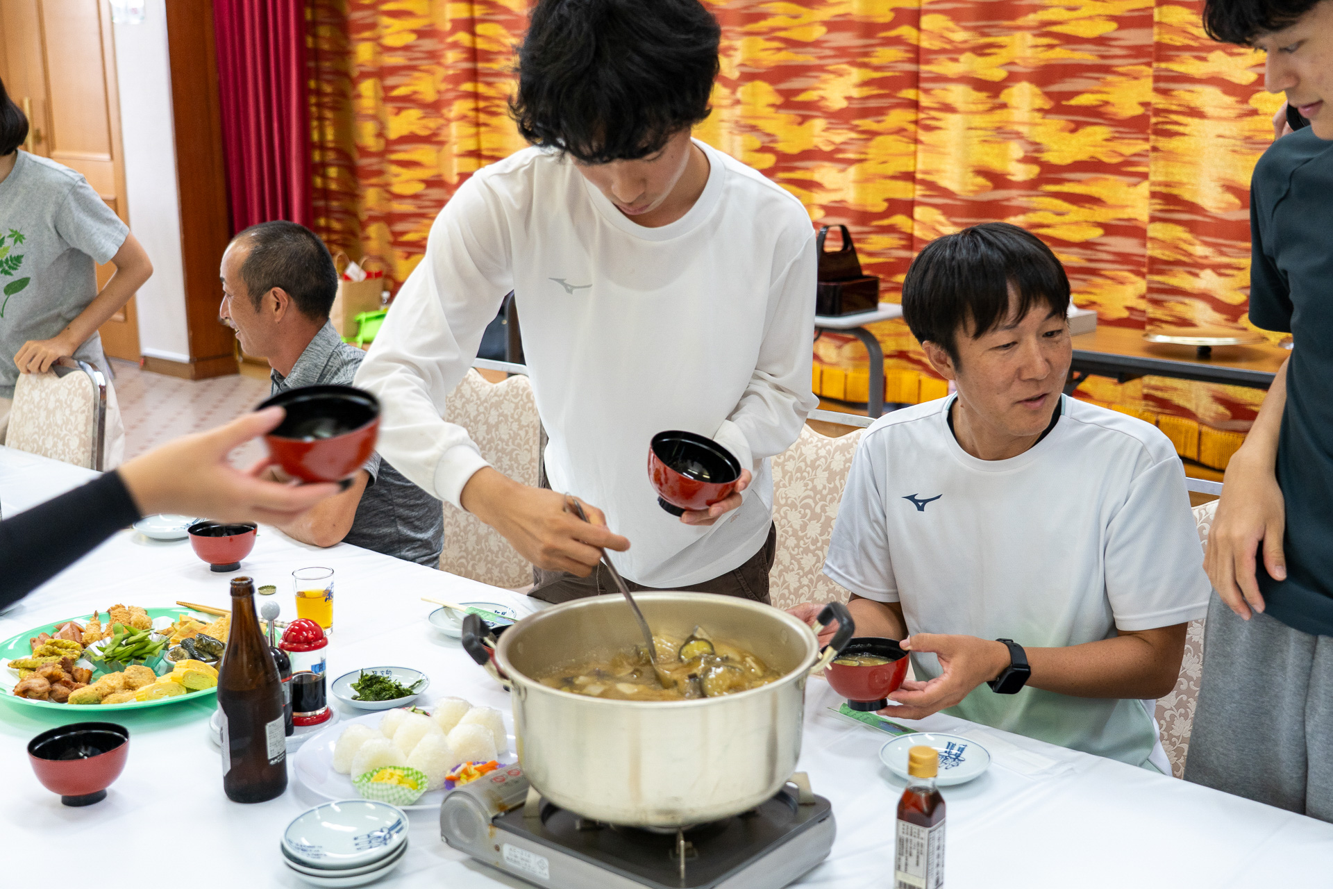 子供たちが出来立ての味噌汁をよそっていく