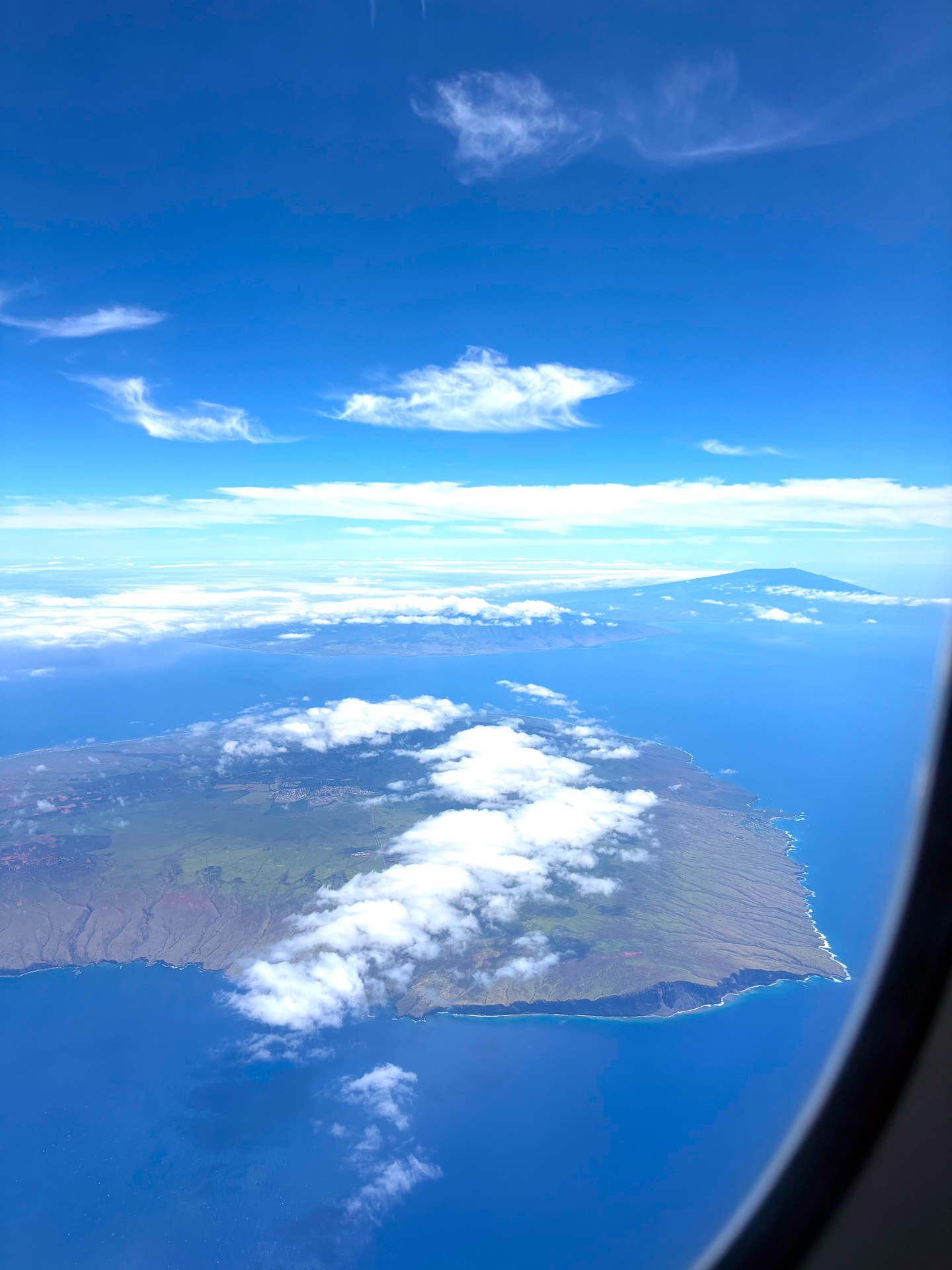 上空から望むラナイ島とその先にはマウイ島のハレアカラの山頂
