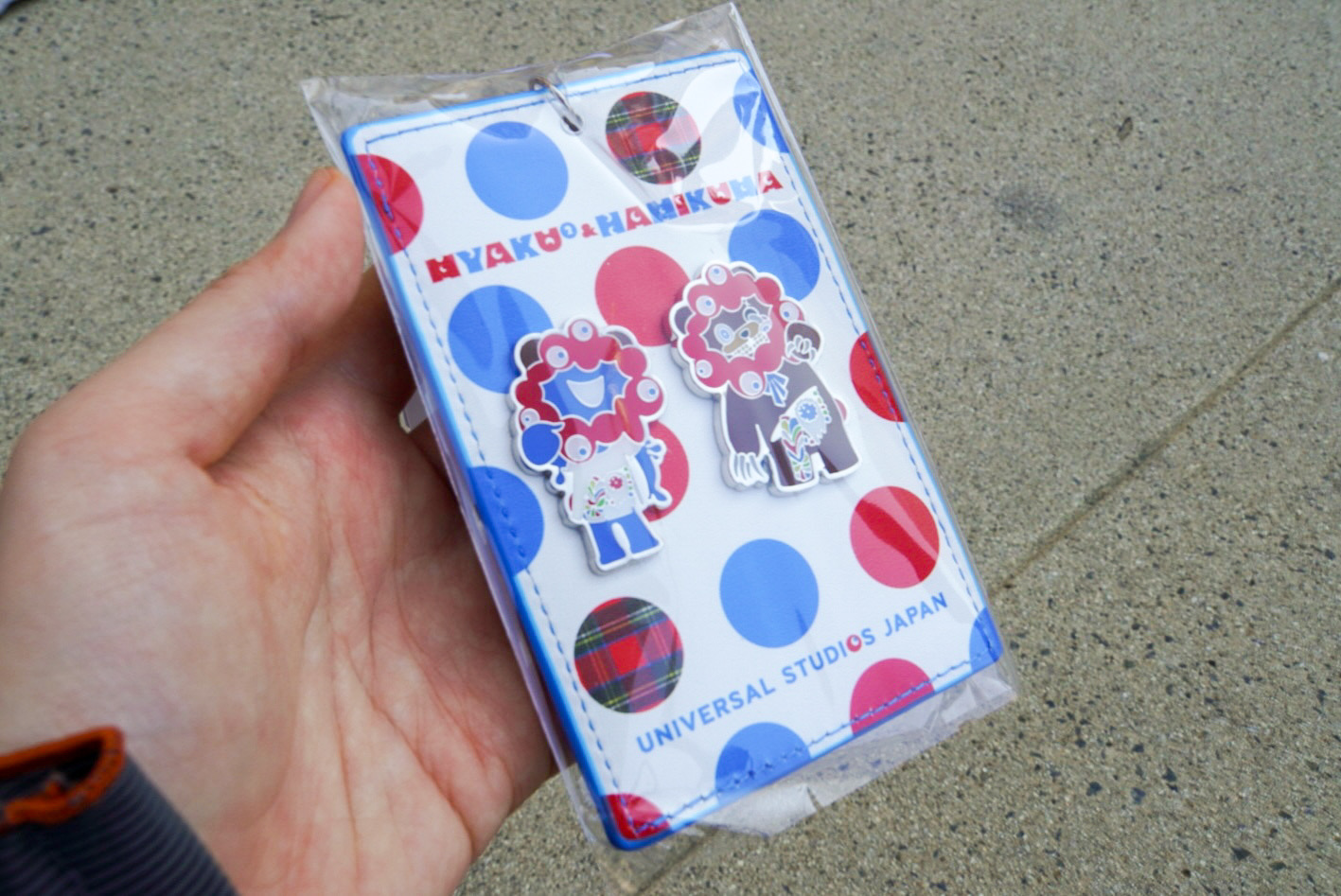 リール付きパスケース（2500円）は、ピンバッジ風のミャクミャクとハミクマが付いている。裏面のデザインにも注目