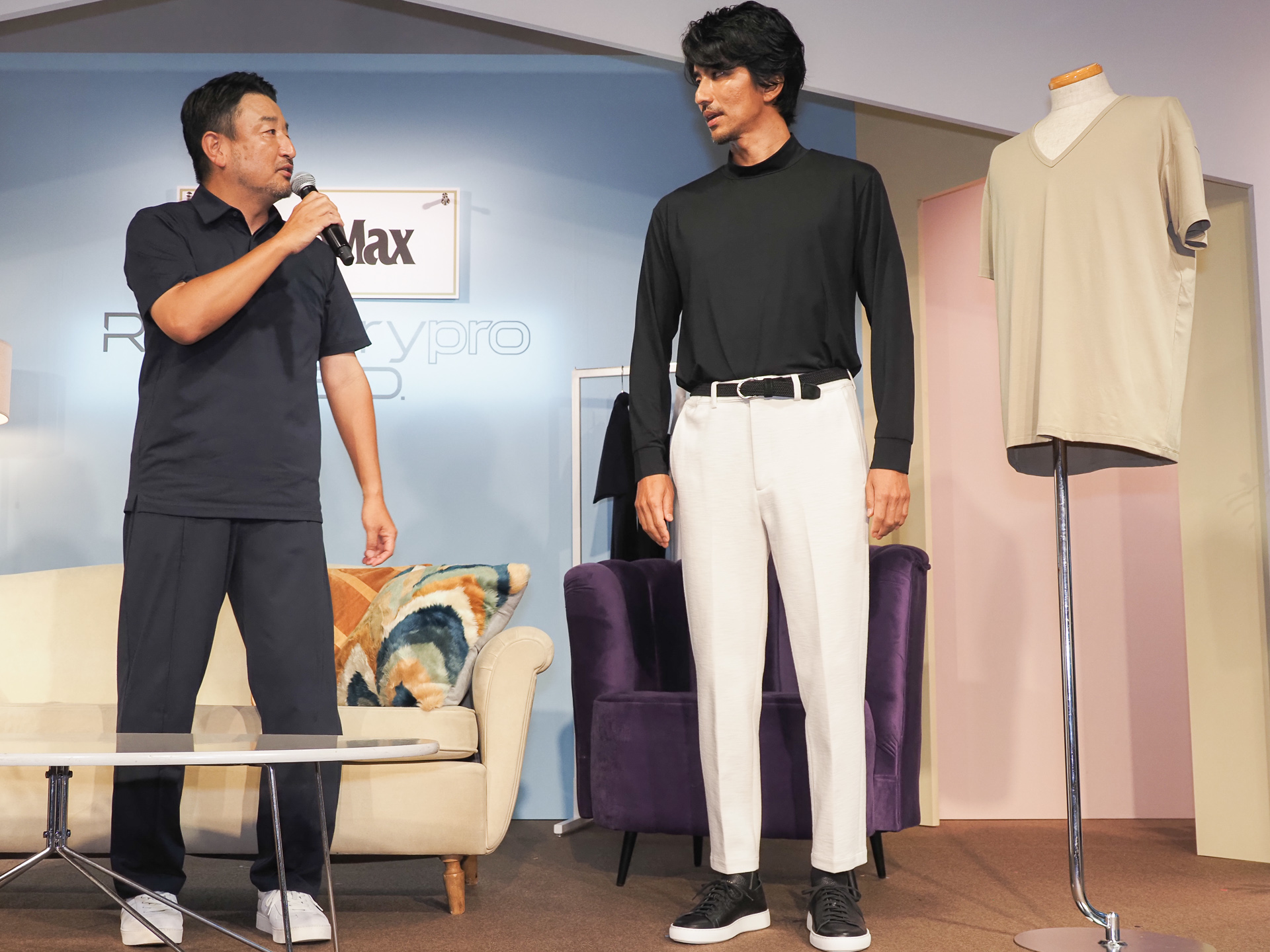 「MonoMax」のコラボレーションモデルを着用。「MonoMax」編集長 奥家慎二氏（左）が半袖ポロシャツとパンツを着用。モデルの幸太さん（中央）がモックネック長袖で上のみ着用。Vネックインナーシャツが置かれている（右）