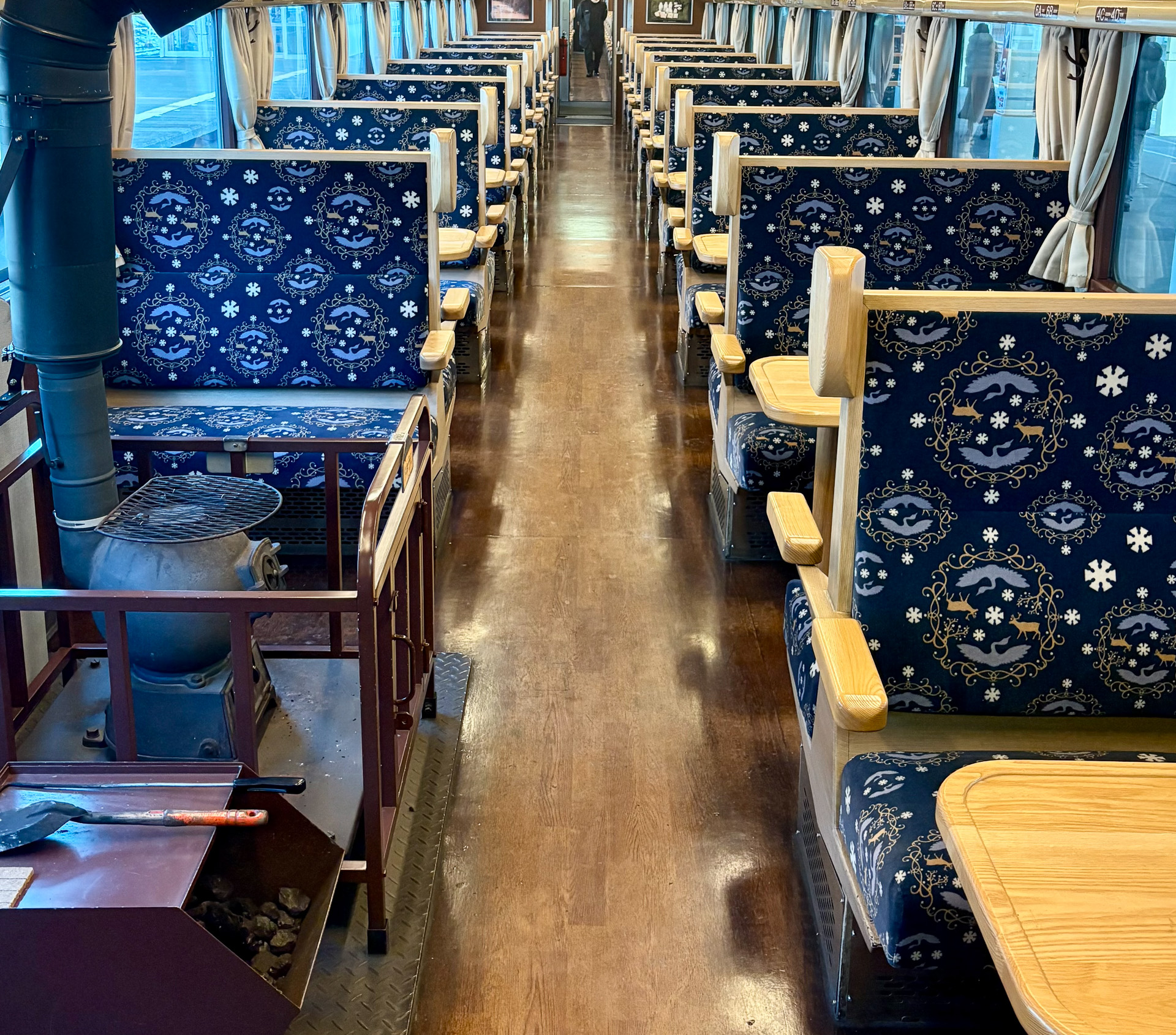 雪の結晶とタンチョウが描かれた座席と、ダルマストーブのあるレトロな車内