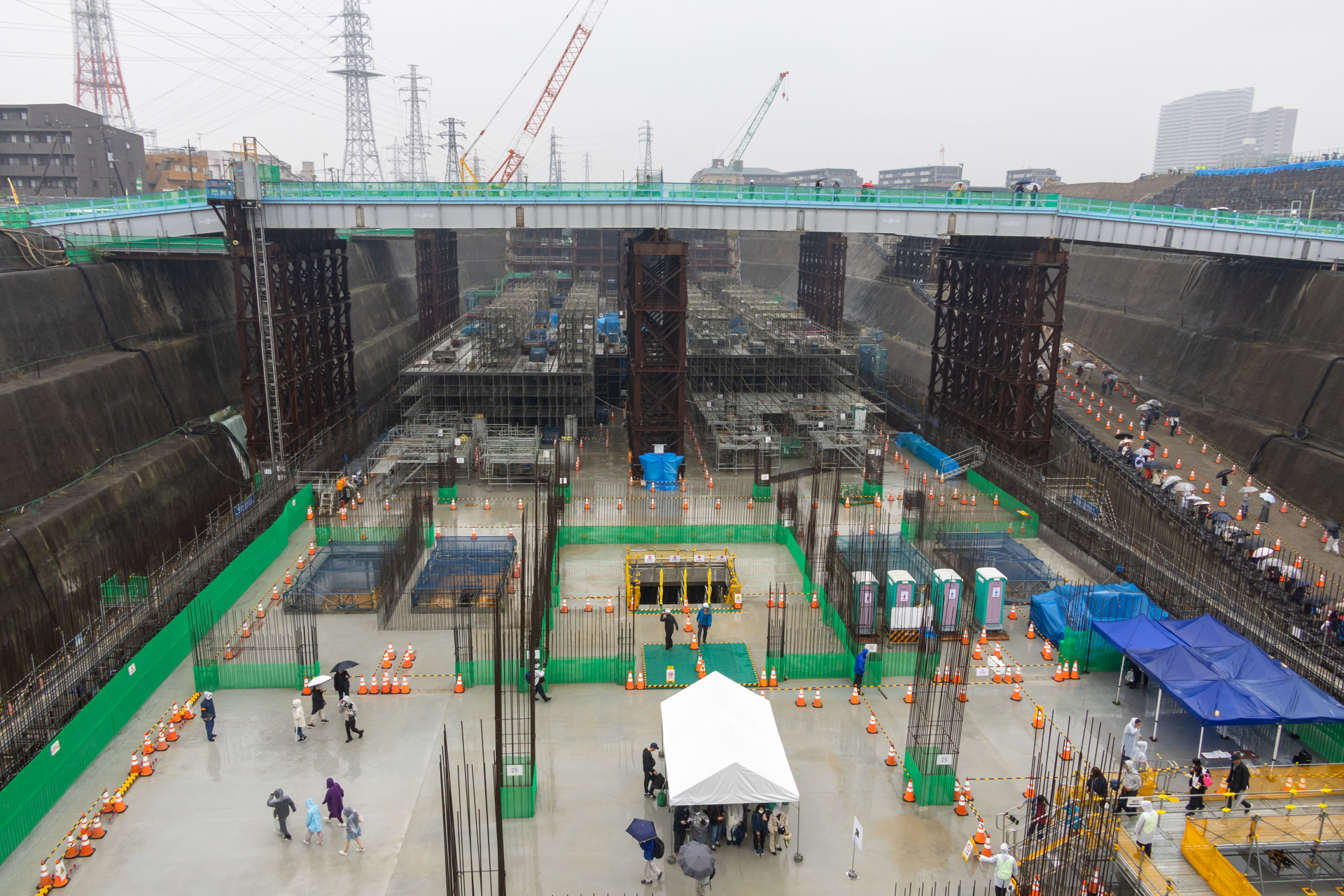 桟橋から神奈川県駅の建設現場を見たところ。真ん中の黄色い柱に囲まれた開口部が地下3階への入口。右奥に見えるのが10mほどの高さに設えた盛土