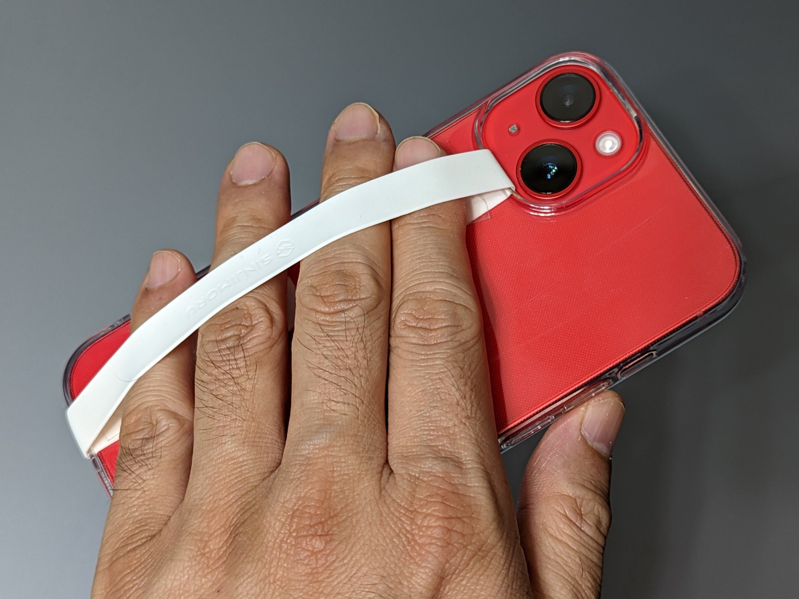 保護ケースのカメラ穴とスピーカー穴を使って一周させるタイプのスマホベルトは、読書時に本体をバランスよく支えるのに最適。装着したままMagSafeが使えるのも利点だ