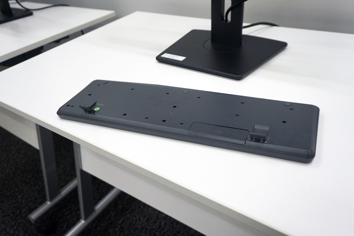 キーボード裏の脚。これを立ててお使いの方も多いと思われるが、仕事上がりにそのまま台座の上に置くと幅広で長方形の台座は座りが悪かった。手前が狭い台形にすることでそのまま置いてもしっかり収まるようになったとか