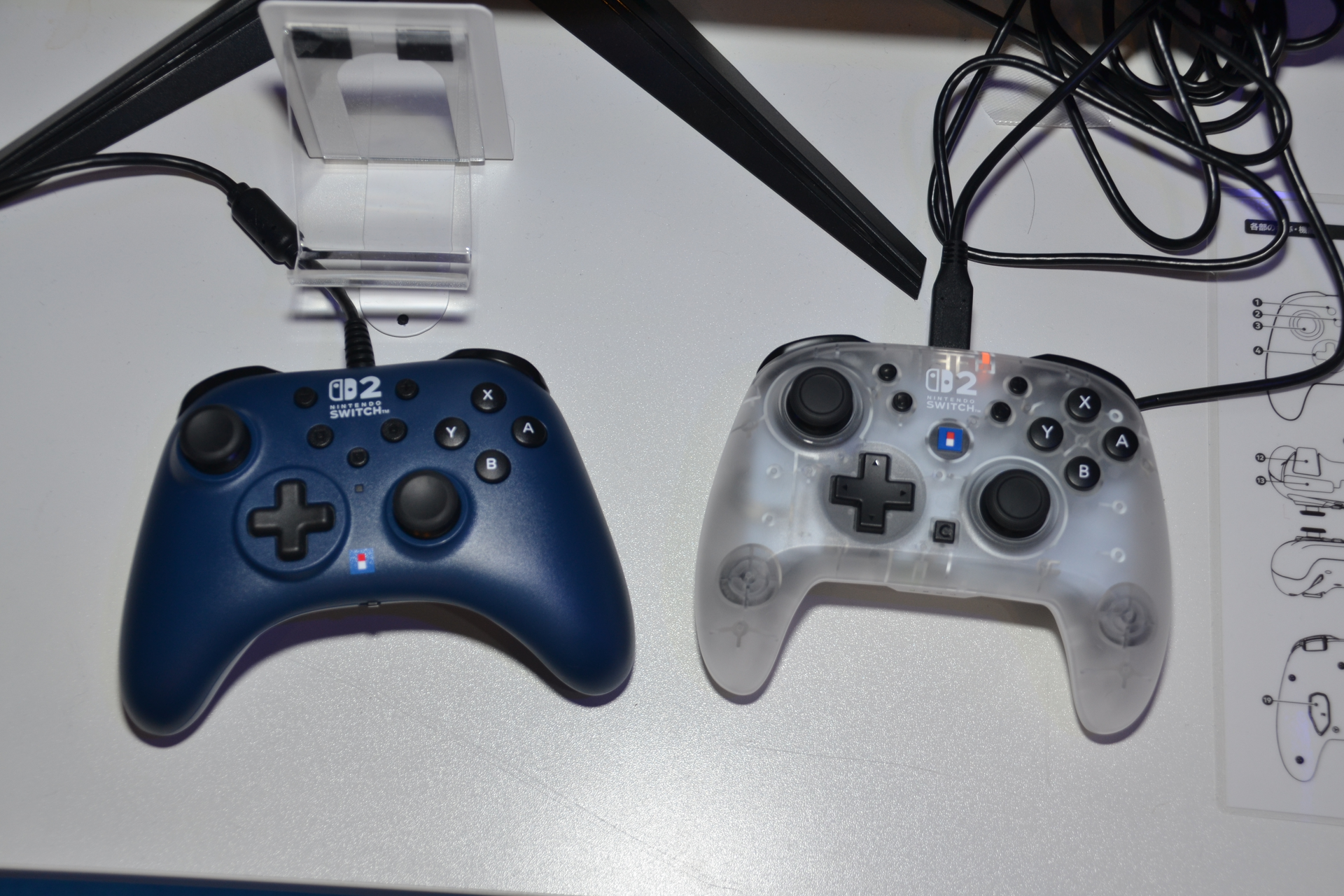 HORIの「<a href="https://hori.jp/products/nsx/nsx-126/" class="n" target="_blank">ワイヤレスホリパッド TURBO for Nintendo Switch 2</a>」（写真右）。発売中の有線タイプ（写真左）とは違い、ジャイロセンサーを内蔵するとともにグリップの角度を変更。重量バランスも調整して、ジャイロ操作の快適性を高めている。アナログスティックに高精度・高耐久のTMRセンサーを採用しているのも特徴。発売は2025年冬としているが、任天堂純正のゲームパッドが著しく品薄なので、注目度が高そうだ