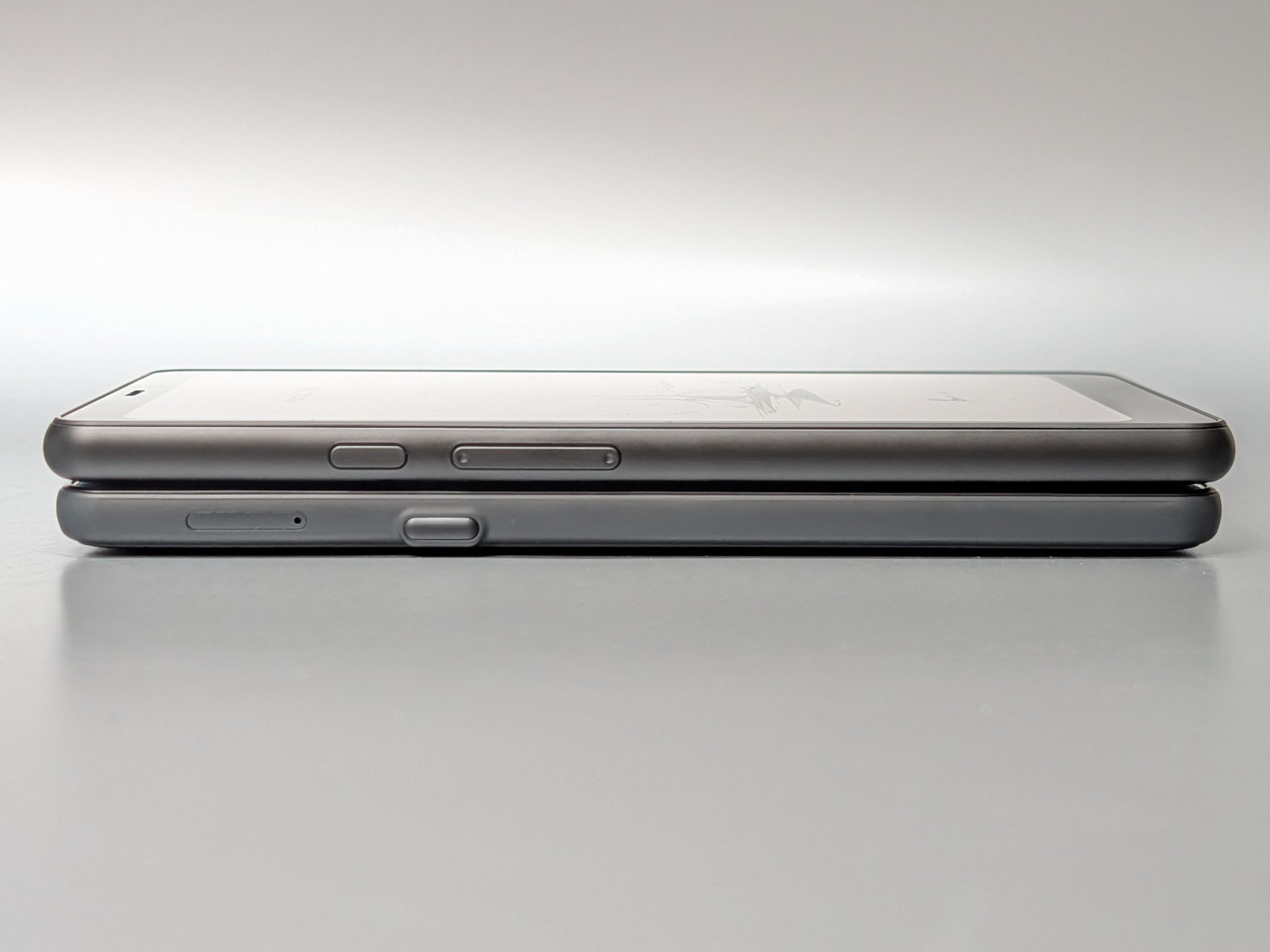 左側面の比較。上がカラーモデル、下がモノクロモデル。カスタムボタンは形状がまったく異なる。またカラーモデルは音量ボタンが、モノクロモデルはカードスロットがこの面にある