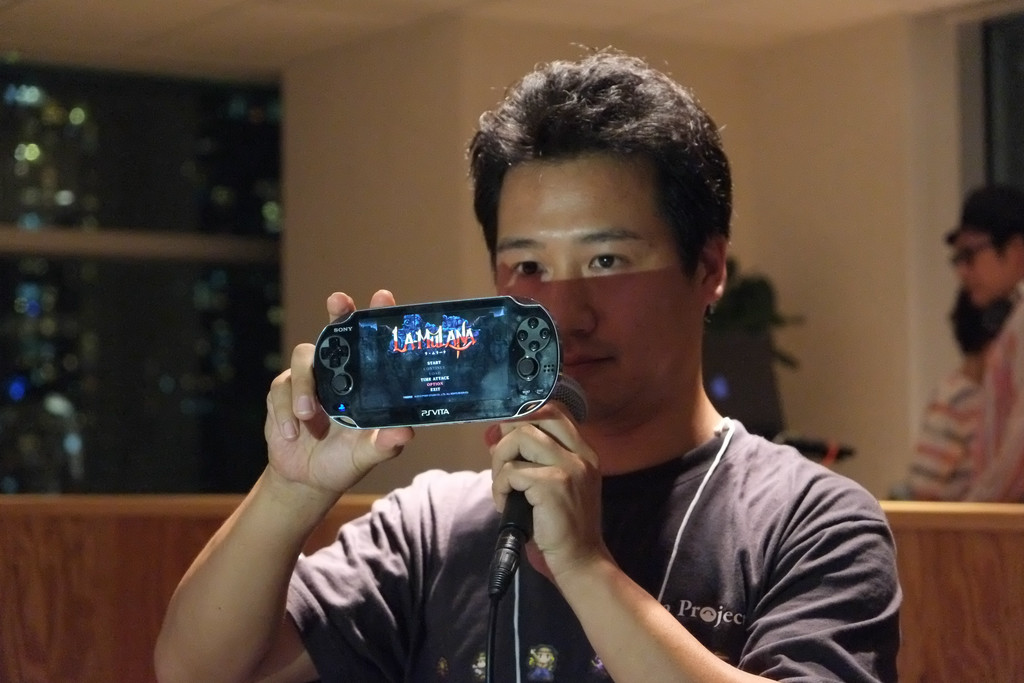 PlayStation Vita上に表示された「LA-MULANA」のタイトル画面を掲げる開発元・NIGOROの楢村氏。ゲーム自体はまだ動作しないとのこと